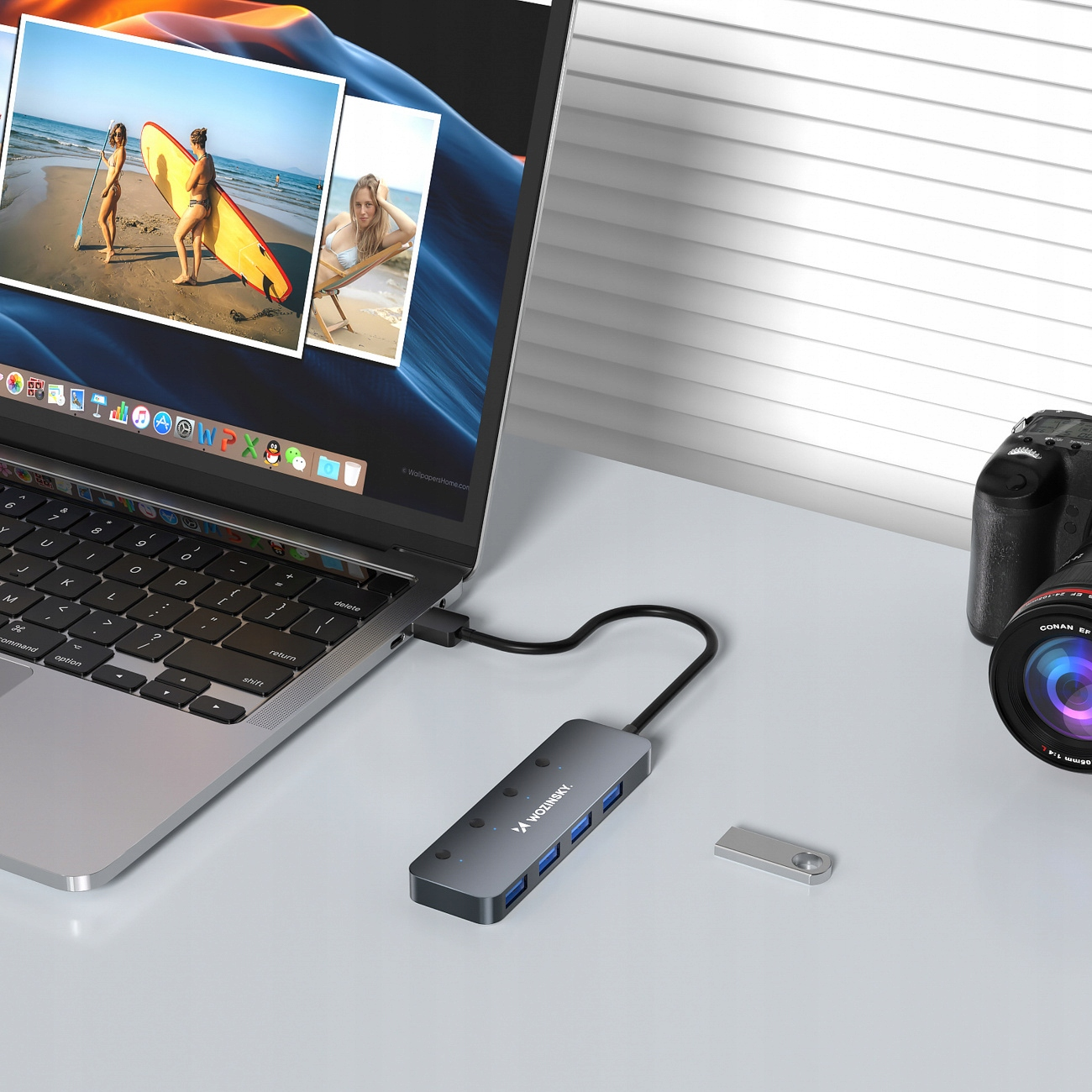 Laptop jest podłączony do huba USB. Zdjęcia i aparat fotograficzny w tle.