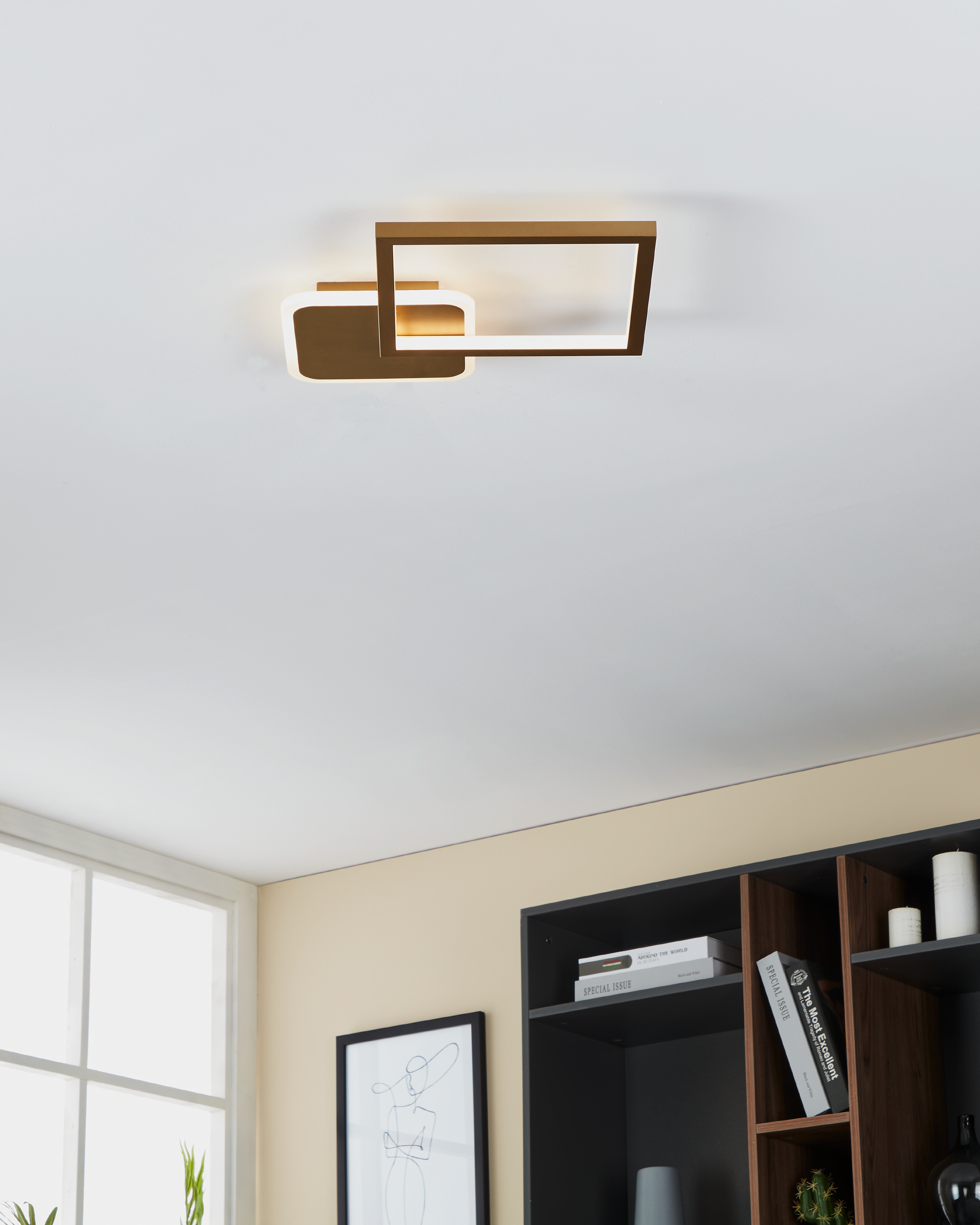 Eine moderne Deckenleuchte mit bronzefarbenen Rechtecken, montiert an einer weißen Decke in einem Raum mit Büchern.