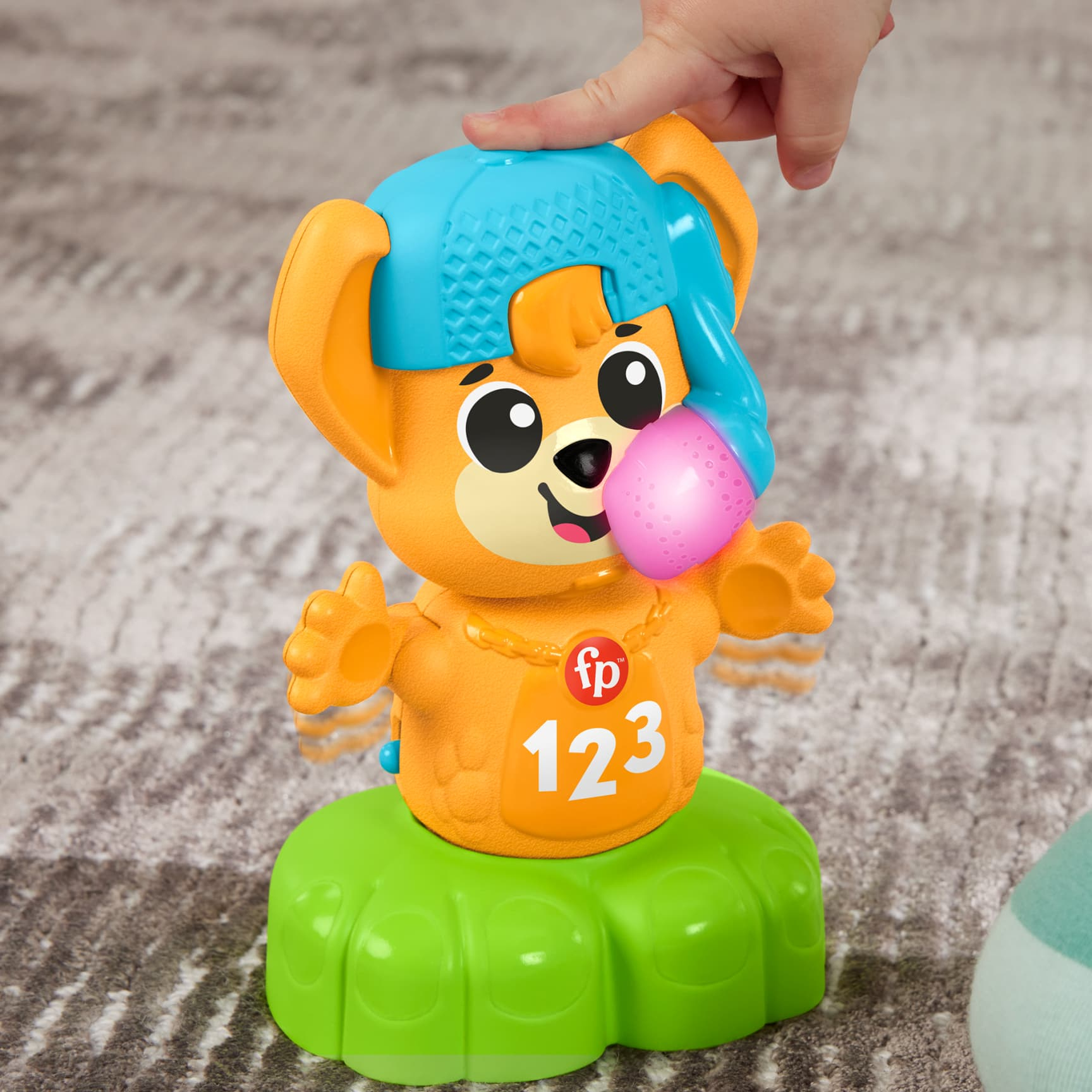 Die Hand eines Kindes interagiert mit einem Spielzeugbären mit blauem Hut und den Zahlen 123.