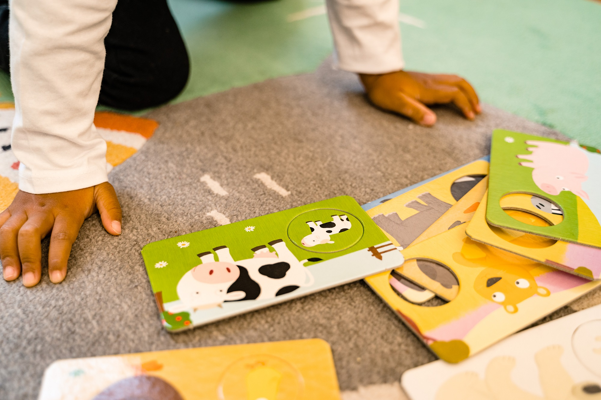 Kinderhände, die auf einem Teppich mit Puzzleteilen spielen.