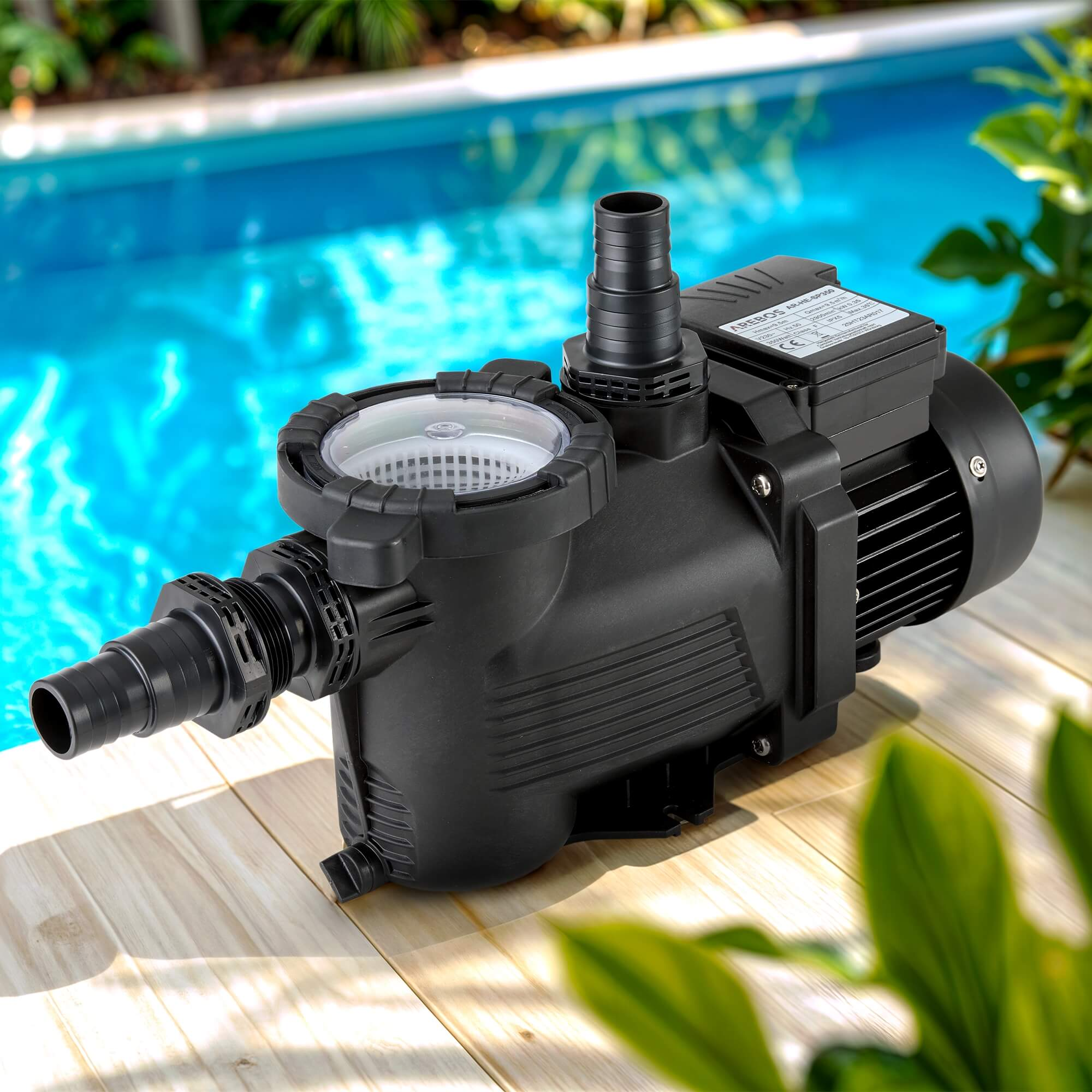 Eine schwarze Poolpumpe mit verschiedenen Aufsätzen, auf einer Holzoberfläche in der Nähe eines Pools.