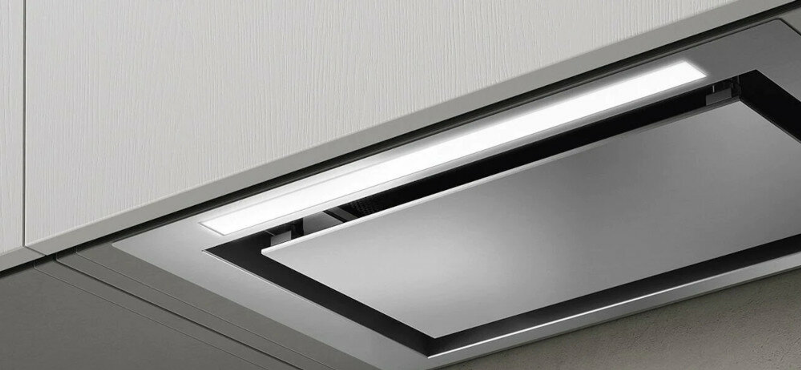 Zbliżenie okapu kuchennego zainstalowanego w kuchni. Okap ma elegancki, minimalistyczny design.