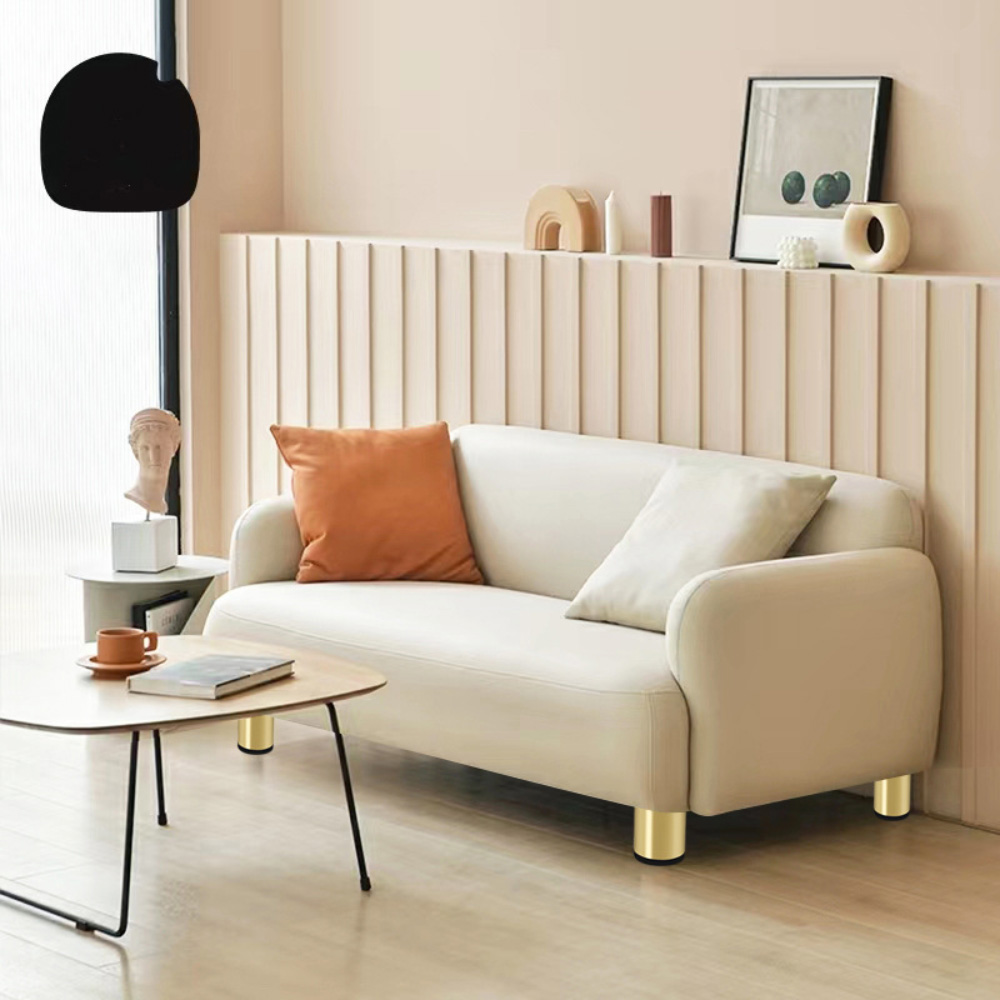 Ein Sofa mit goldenen Beinen. Im Hintergrund ein Couchtisch und andere Objekte.