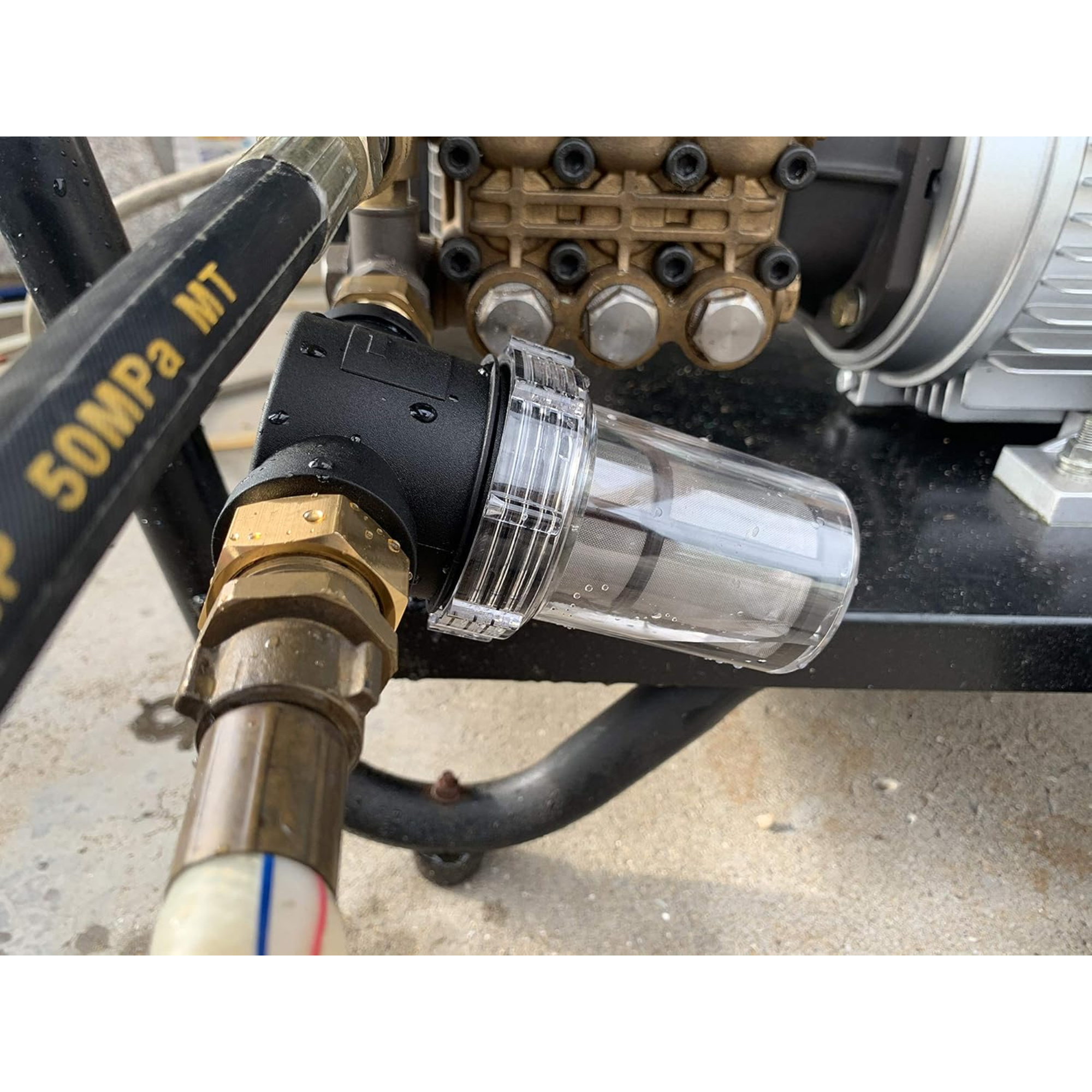 Ein klarer Wasserfilter mit Messingarmaturen. Der Filter ist an einem schwarzen Schlauch befestigt.
