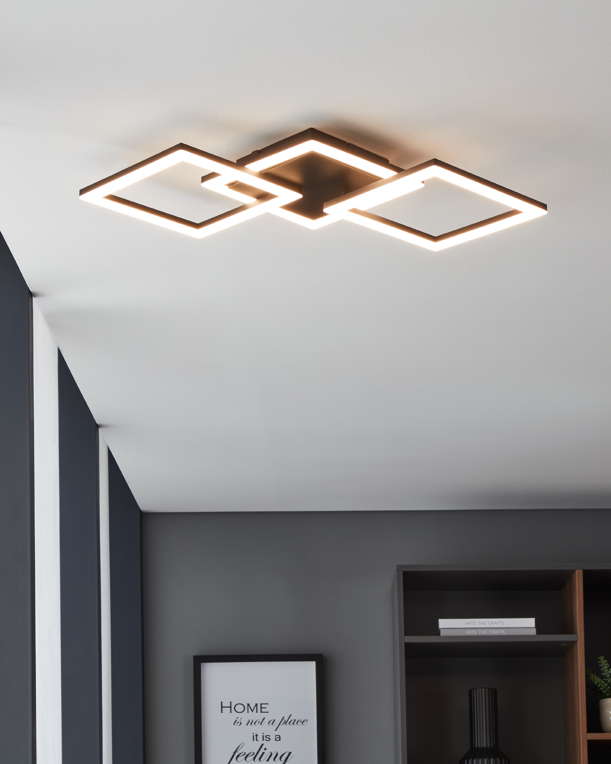 Lampada da soffitto con tre lampade quadrate. La stanza ha pareti grigie e una parete di accento grigio scuro.