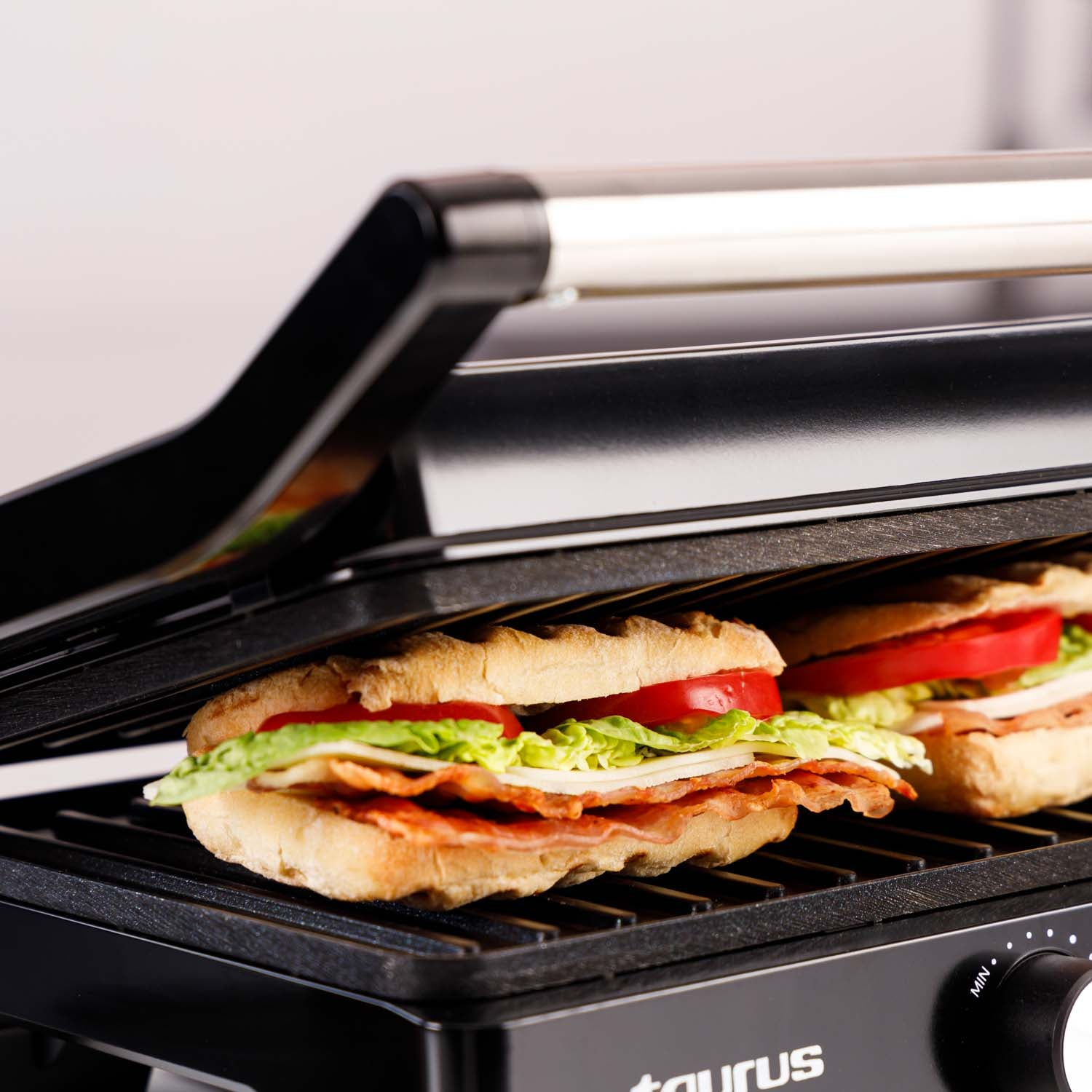 Nahaufnahme eines Grills mit zwei Sandwiches. Die Sandwiches haben Fleisch, Salat und Tomaten.