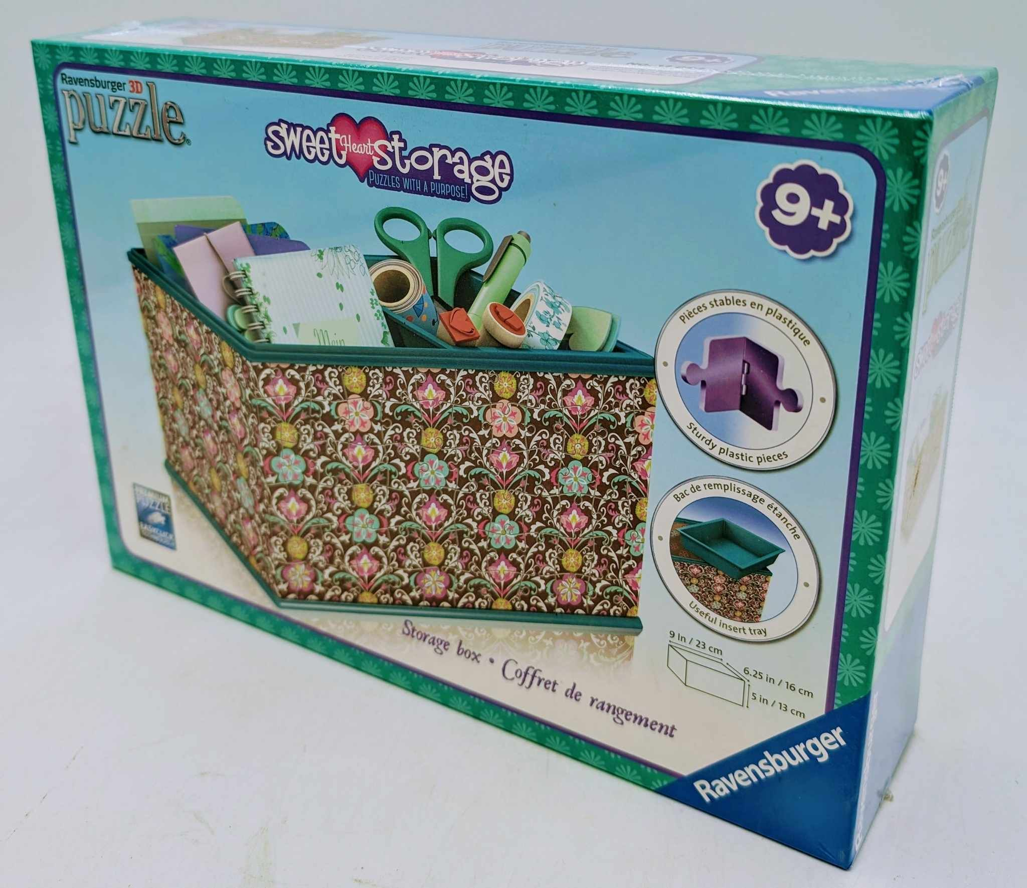Eine Aufbewahrungsbox mit Blumenmuster und verschiedenen Bastelmaterialien, darunter Schere und Klebeband.