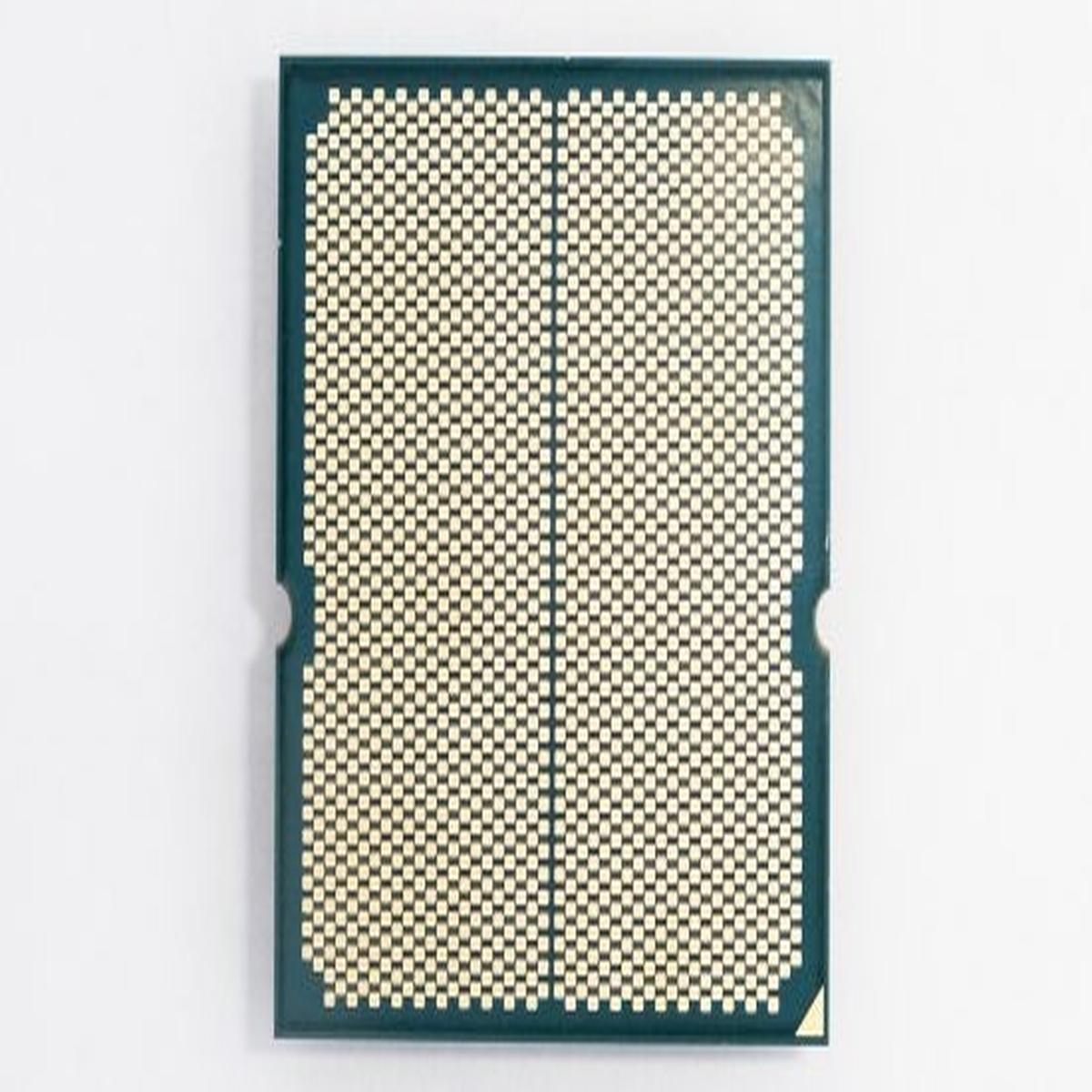 Procesor CPU z góry. Ma wzór siatki ze złotych kwadratów i dwa wycięcia. Tło jest białe.