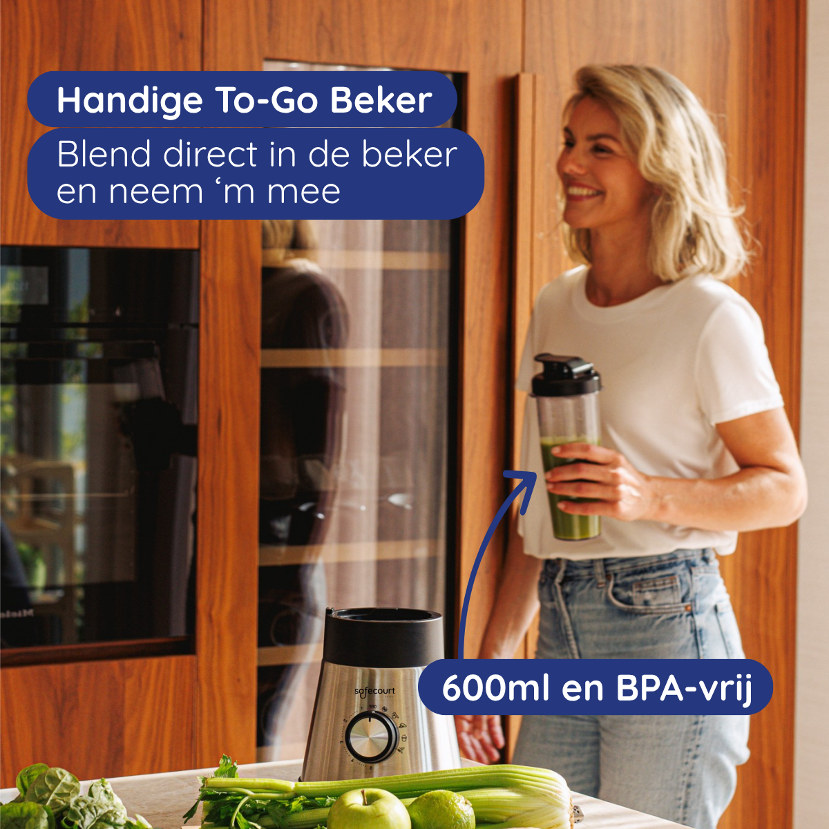 Een vrouw houdt een blenderfles met groene vloeistof vast, naast een blender en groenten.