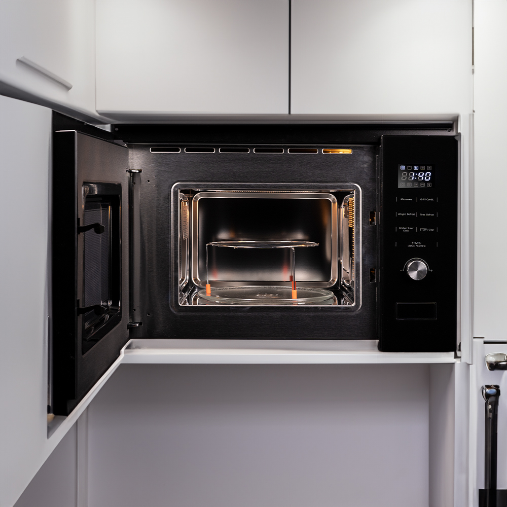 Un horno microondas negro abierto, que revela un plato de vidrio y una rejilla de metal. La pantalla muestra la hora. La puerta está abierta.