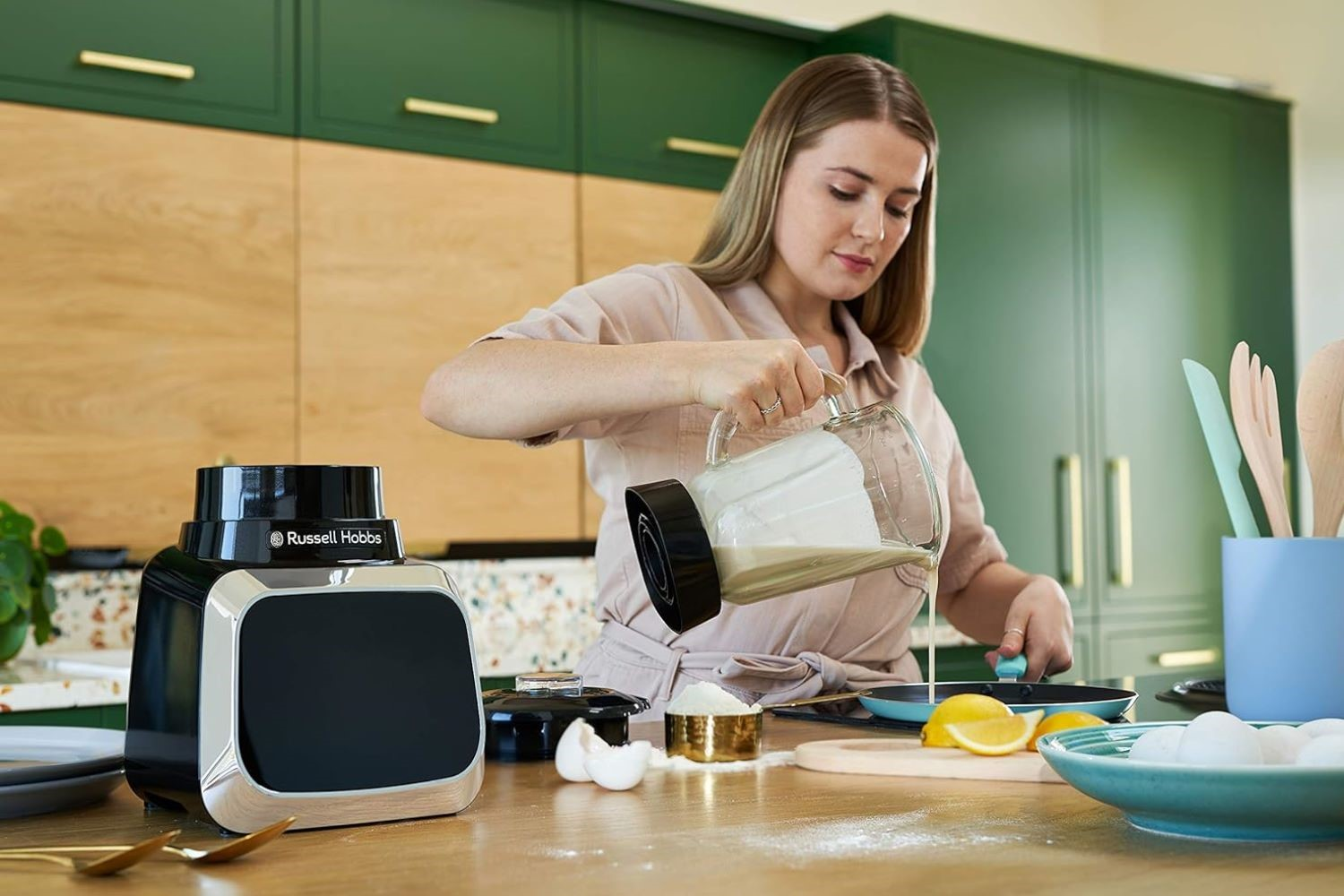 Frau gießt Smoothie aus dem Mixer in eine Pfanne mit Eiern und Zitronen. Küchenumgebung.