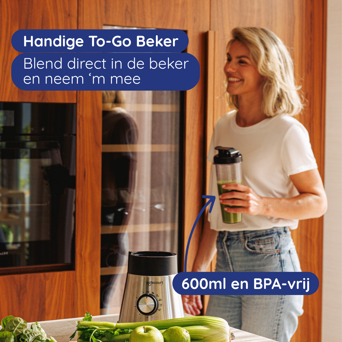 Een vrouw in een keuken houdt een blenderfles vast. De blender staat op het aanrecht met groene groenten.