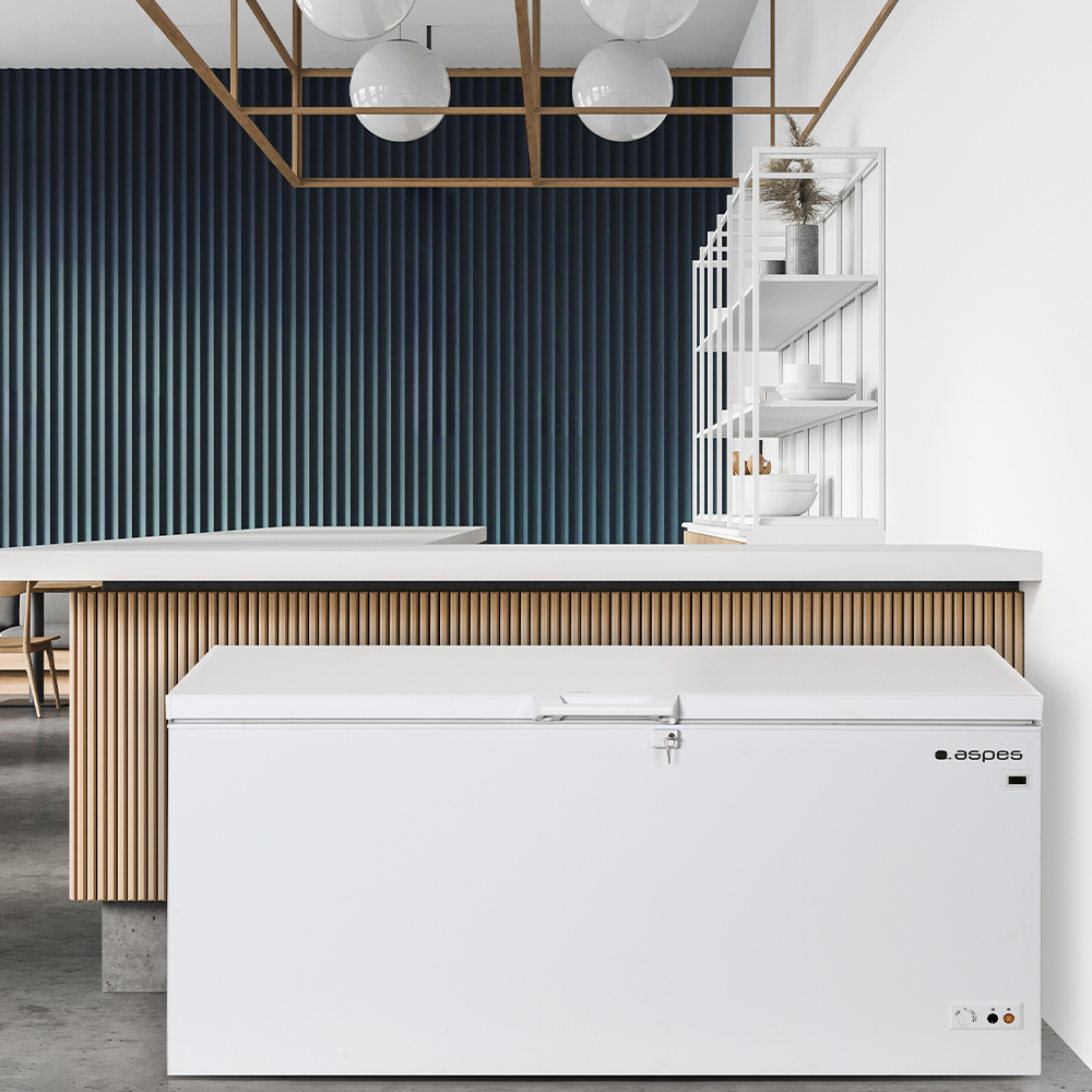 Un congelador horizontal blanco se coloca en una cocina moderna con detalles en blanco y madera.