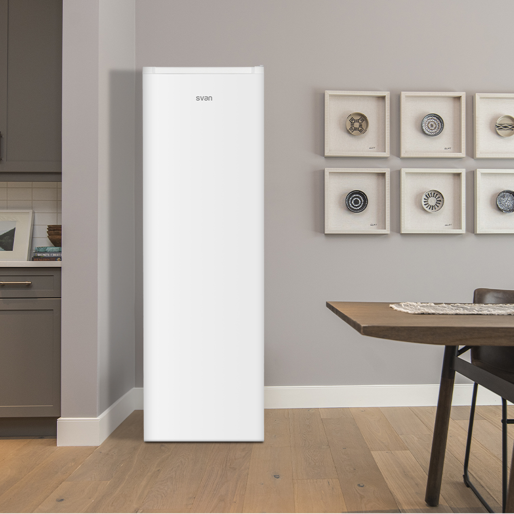 Refrigerador blanco en habitación con piso de madera, paredes grises y obras de arte enmarcadas en la pared.