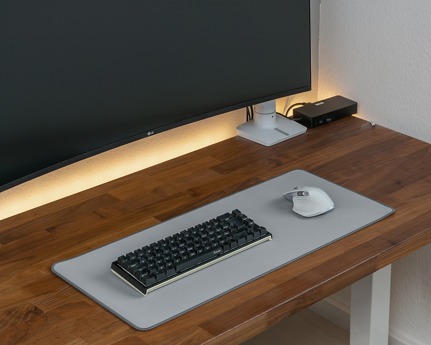 Ein Schreibtisch mit Computermonitor, Tastatur und Maus. Auf dem Schreibtisch befindet sich ein Mauspad.