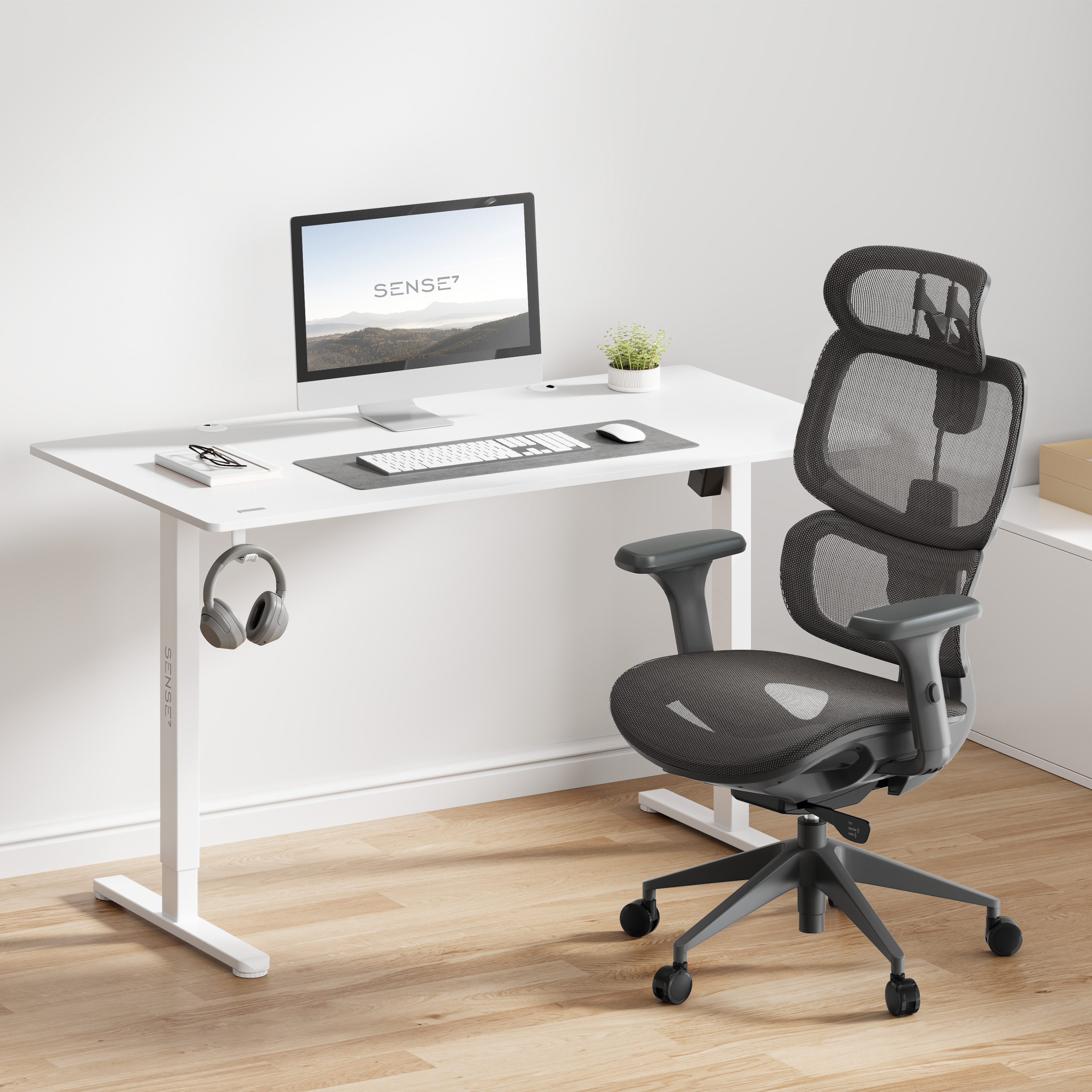 Moderne kantooropstelling: witte bureau, computer, koptelefoon, zwarte bureaustoel met gaas en een kleine plant op houten vloer.