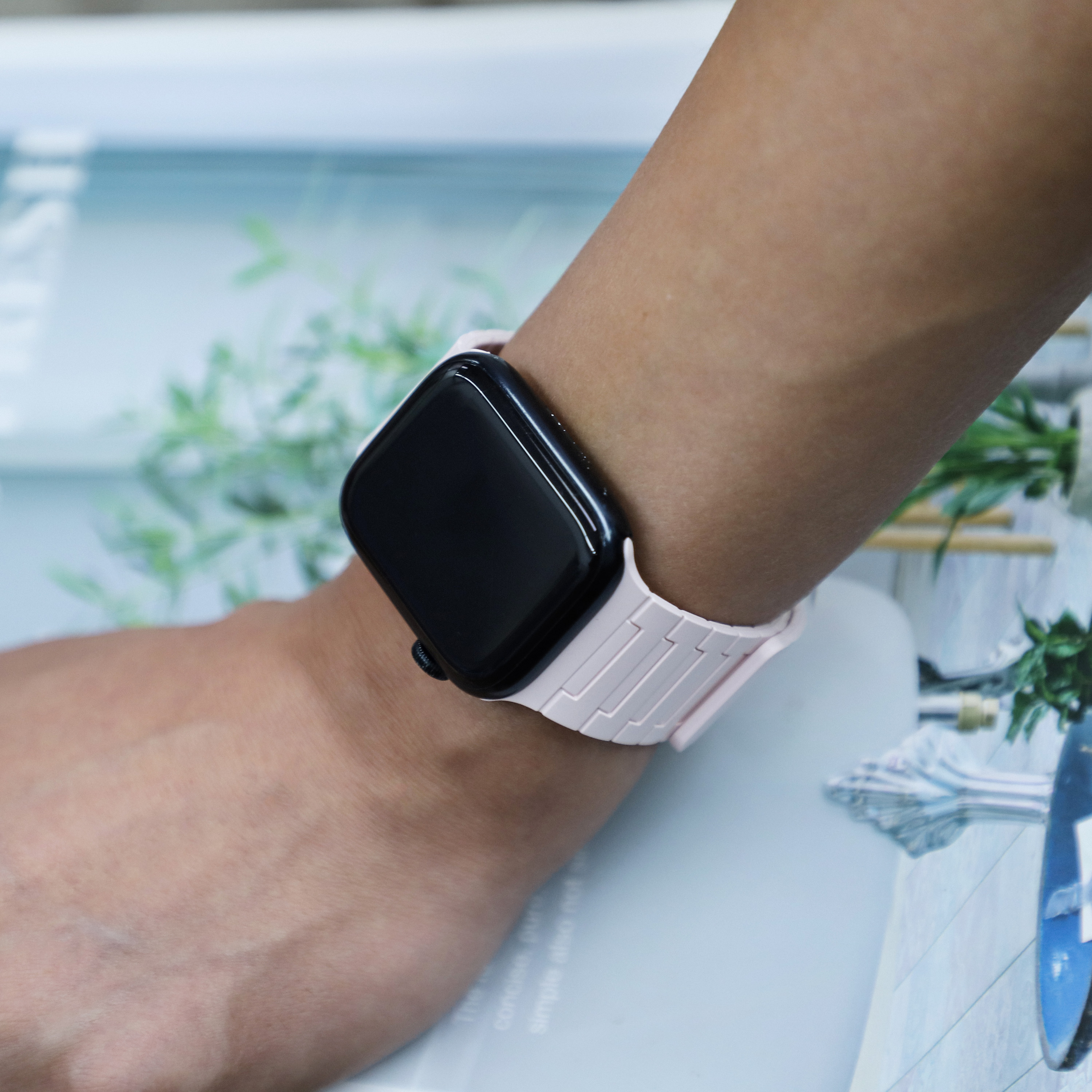 Ein Handgelenk mit einer Smartwatch. Das Armband ist hellrosa, das Zifferblatt schwarz.