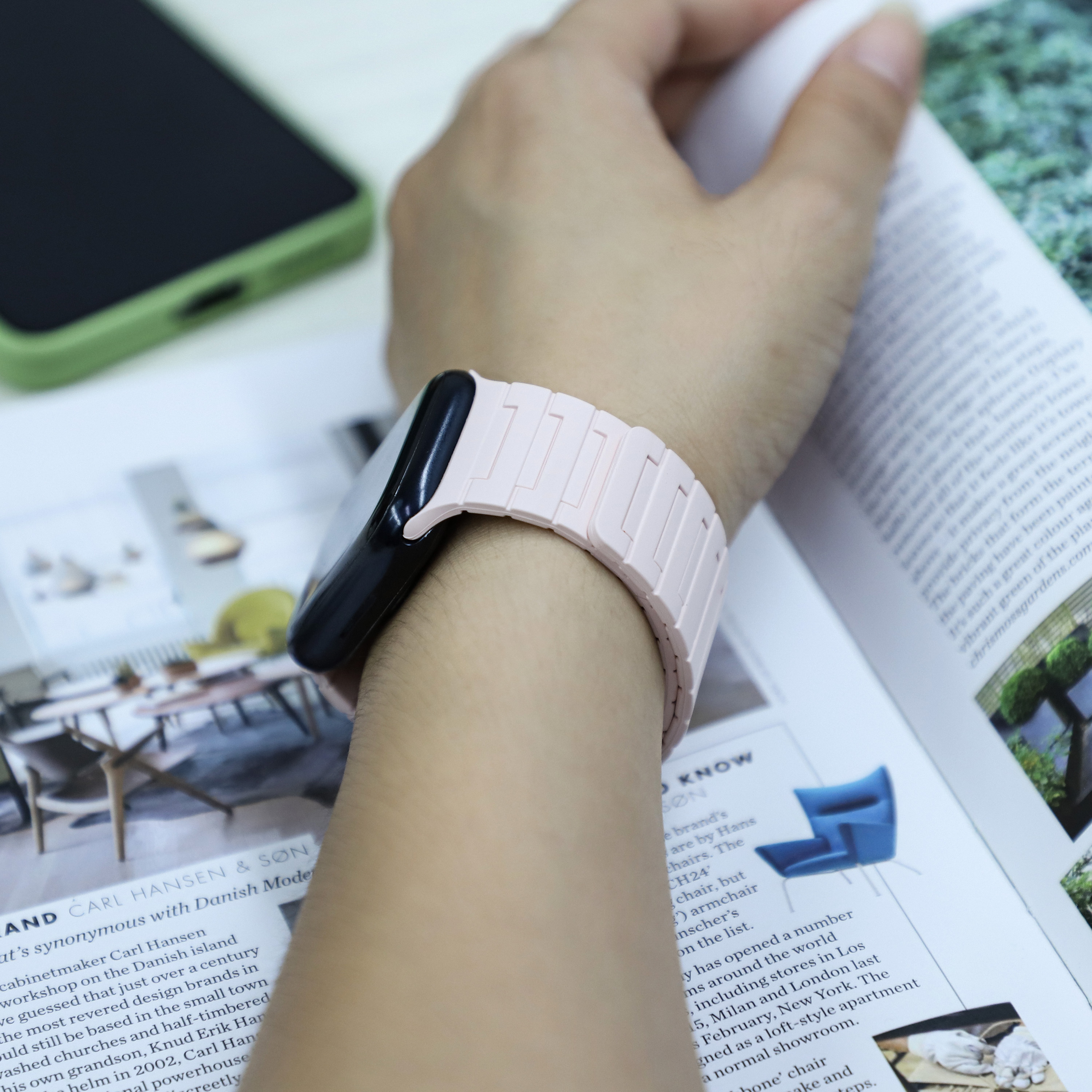 Handgelenk einer Person mit pinkem Armband, hält ein offenes Magazin.