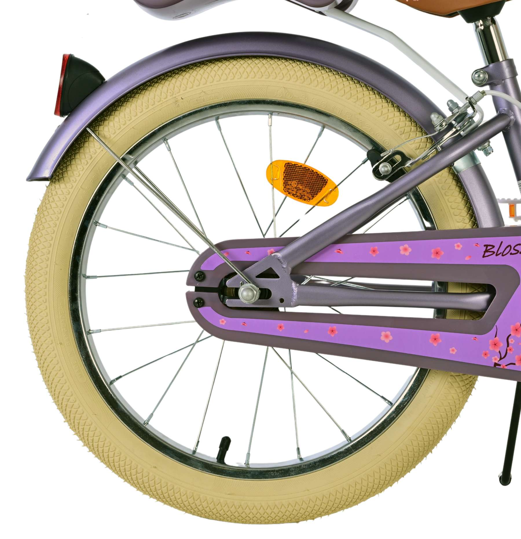 Nahaufnahme des Hinterrads eines lila Fahrrads. Das Rad hat beige Reifen und ein Blumendesign auf dem Schutzblech.
