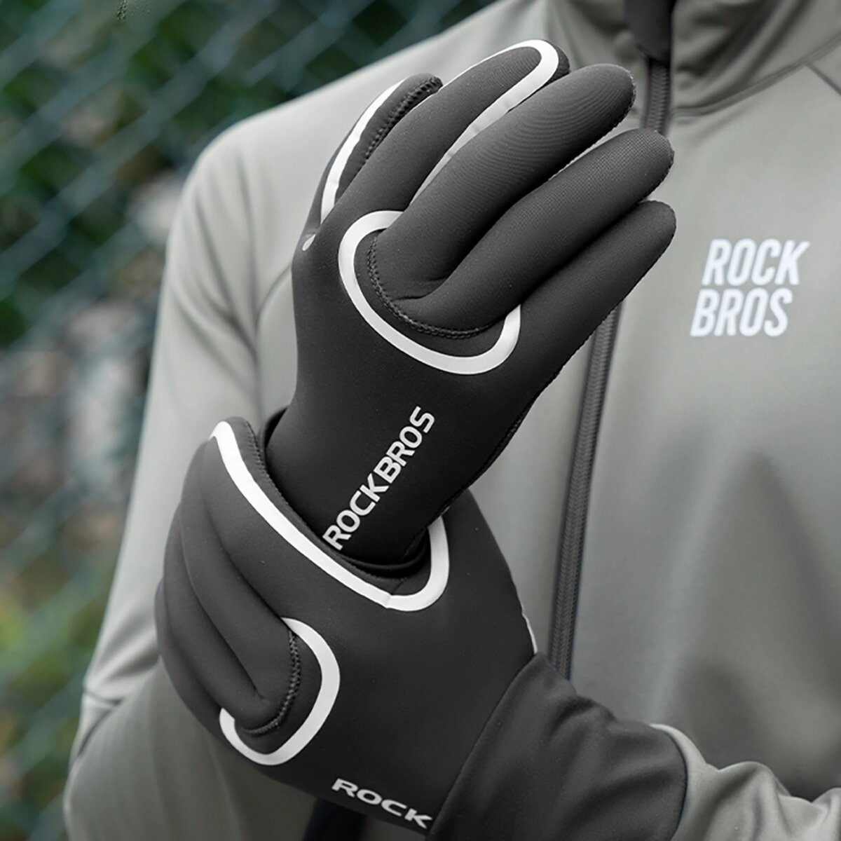 Schwarze Fahrradhandschuhe mit weißen Akzenten und ROCKBROS-Logo. Eine Person trägt die Handschuhe.