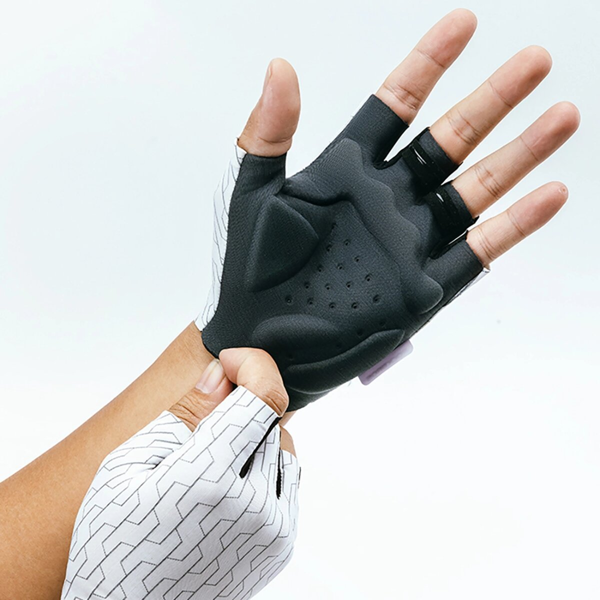 Hände, die weiß-schwarze Radhandschuhe tragen, eine Hand passt den anderen Handschuh an.