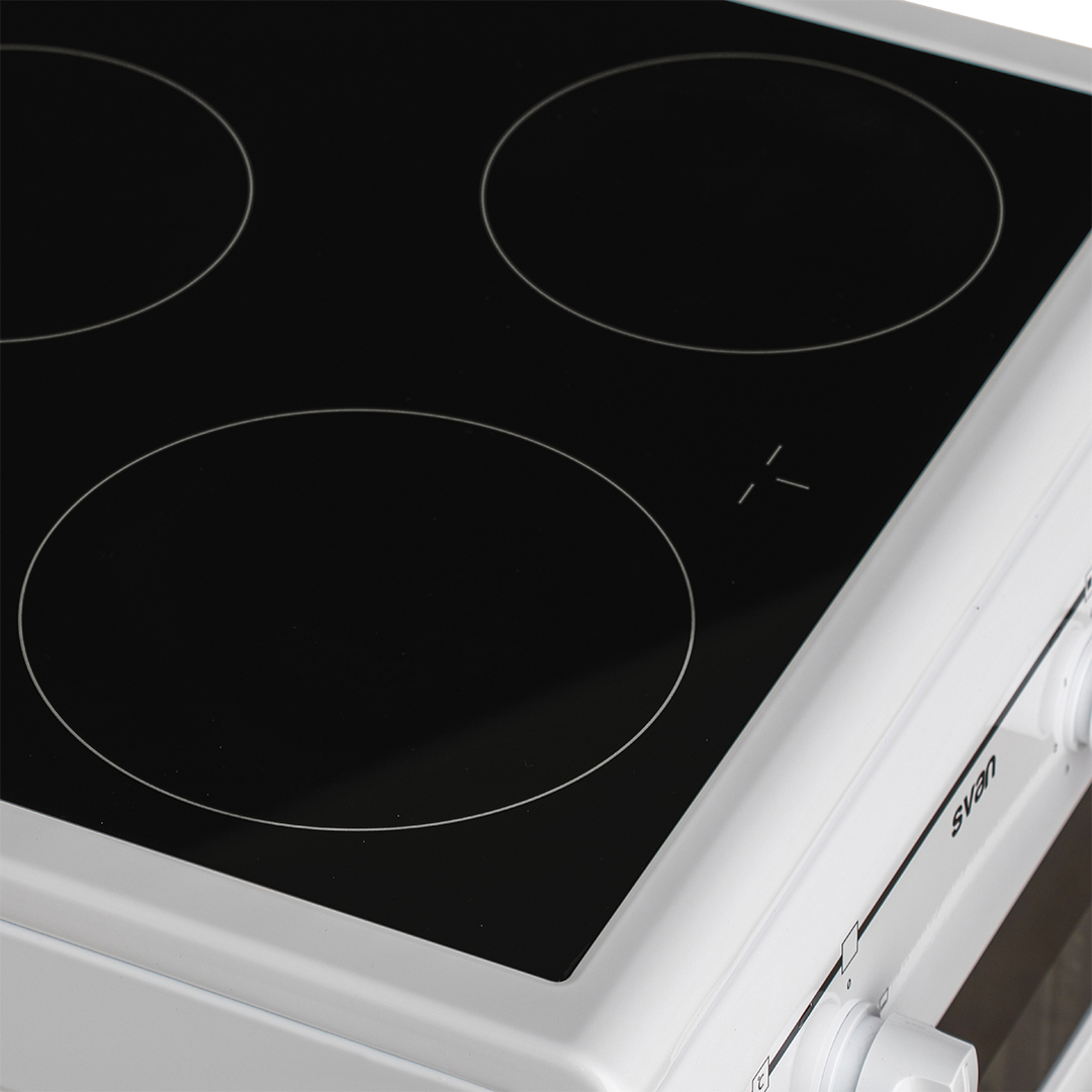 Primer plano de una placa de cocina eléctrica negra con cuatro quemadores circulares. La estufa es blanca.
