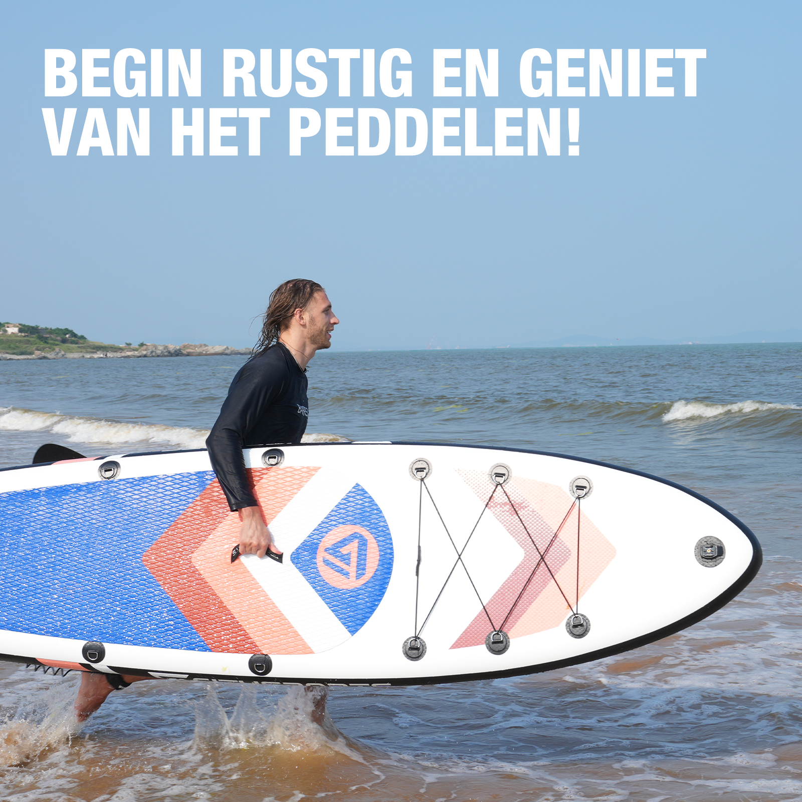 Man draagt een paddleboard het water in. Het paddleboard is blauw, rood en wit. Het water is blauw.