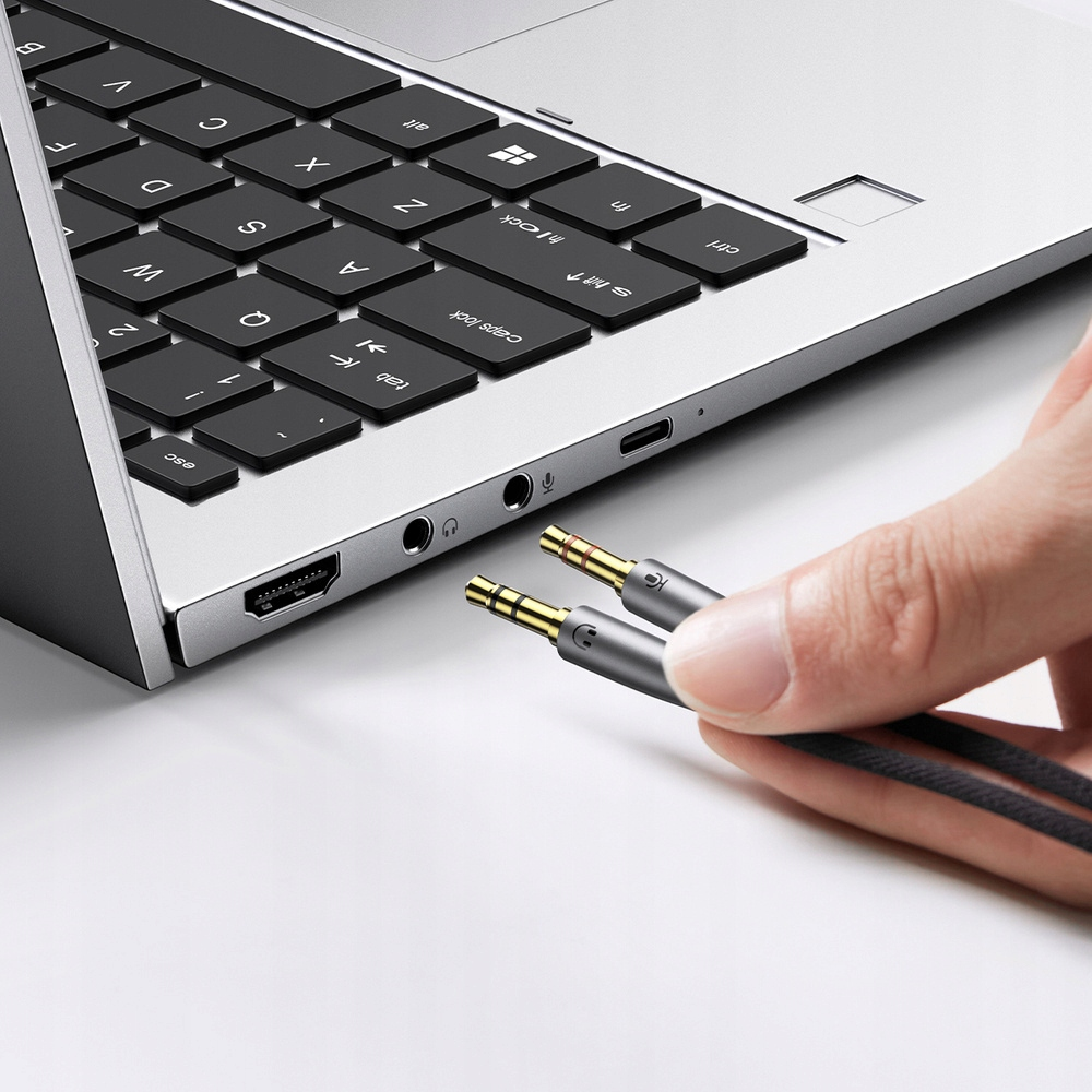 Un laptop con due cavi audio collegati. I cavi sono argento e neri.
