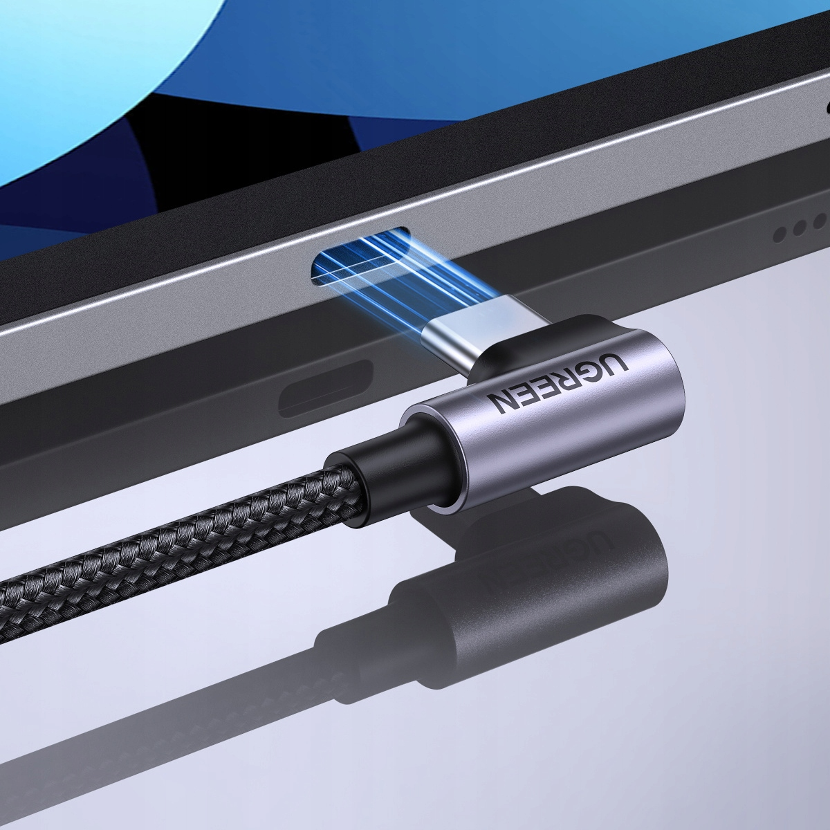 Srebrne złącze kątowe USB-C UGREEN wpięte w urządzenie, z plecionym kablem, zbliżenie.