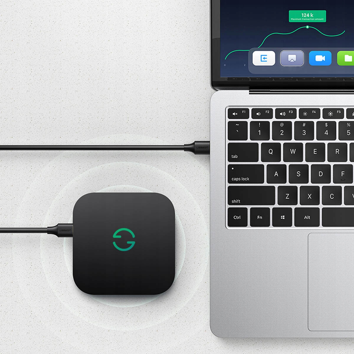 Czarne urządzenie podłączone do laptopa za pomocą białego kabla ładującego. Wykres znajduje się na ekranie laptopa.