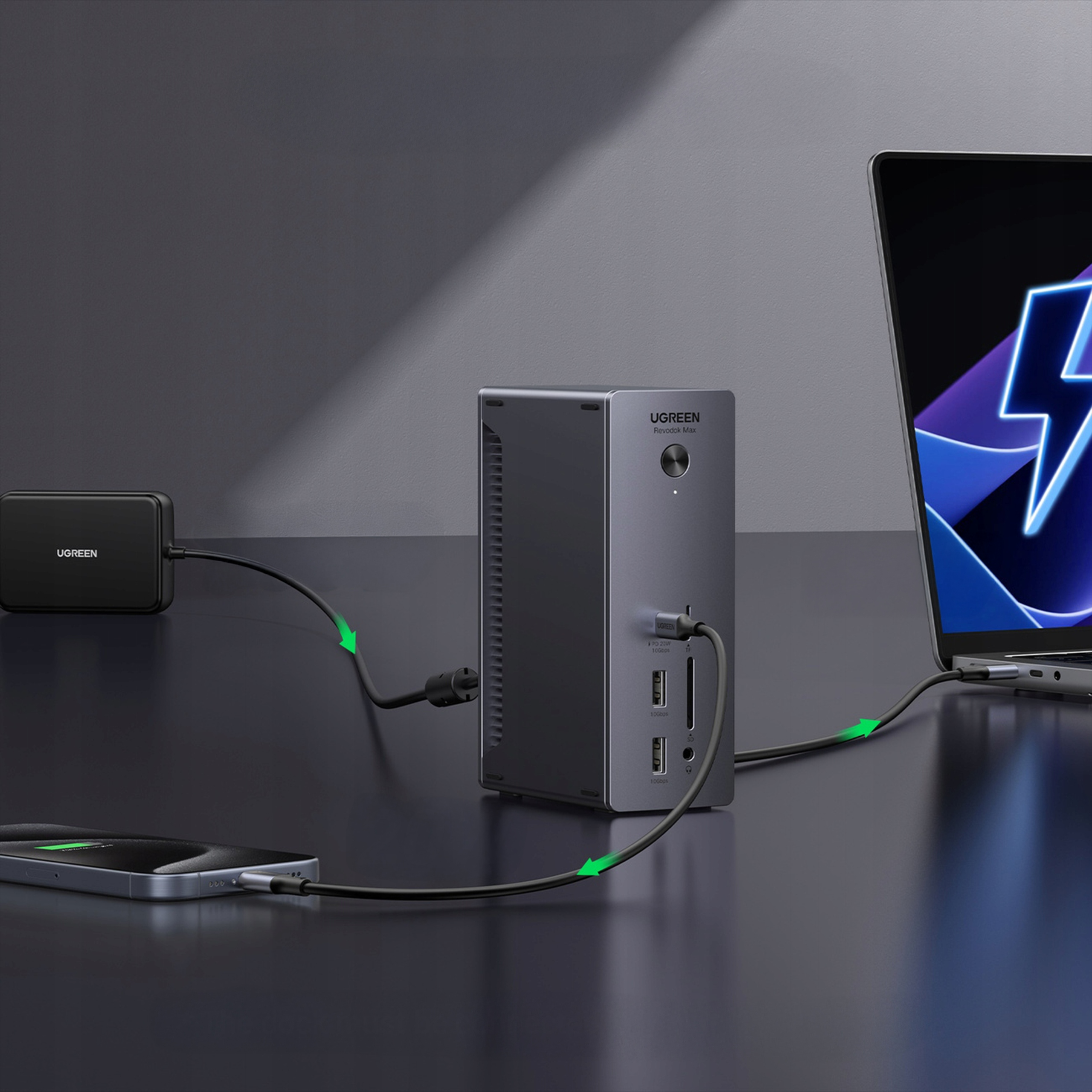 Czarny hub z podłączonym laptopem i telefonem. Zielone strzałki pokazują połączenia kablowe. Ciemne tło.