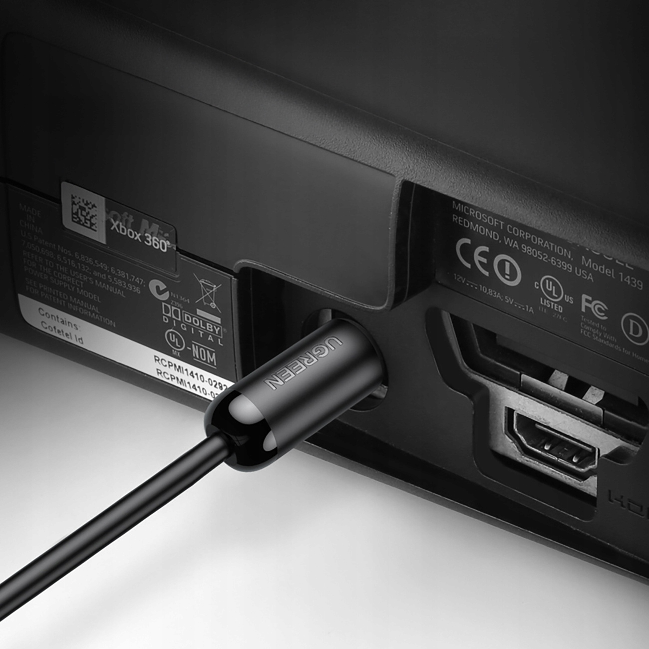Czarny kabel UGREEN podłączony do konsoli Xbox 360. Widoczny port HDMI. Zbliżenie.
