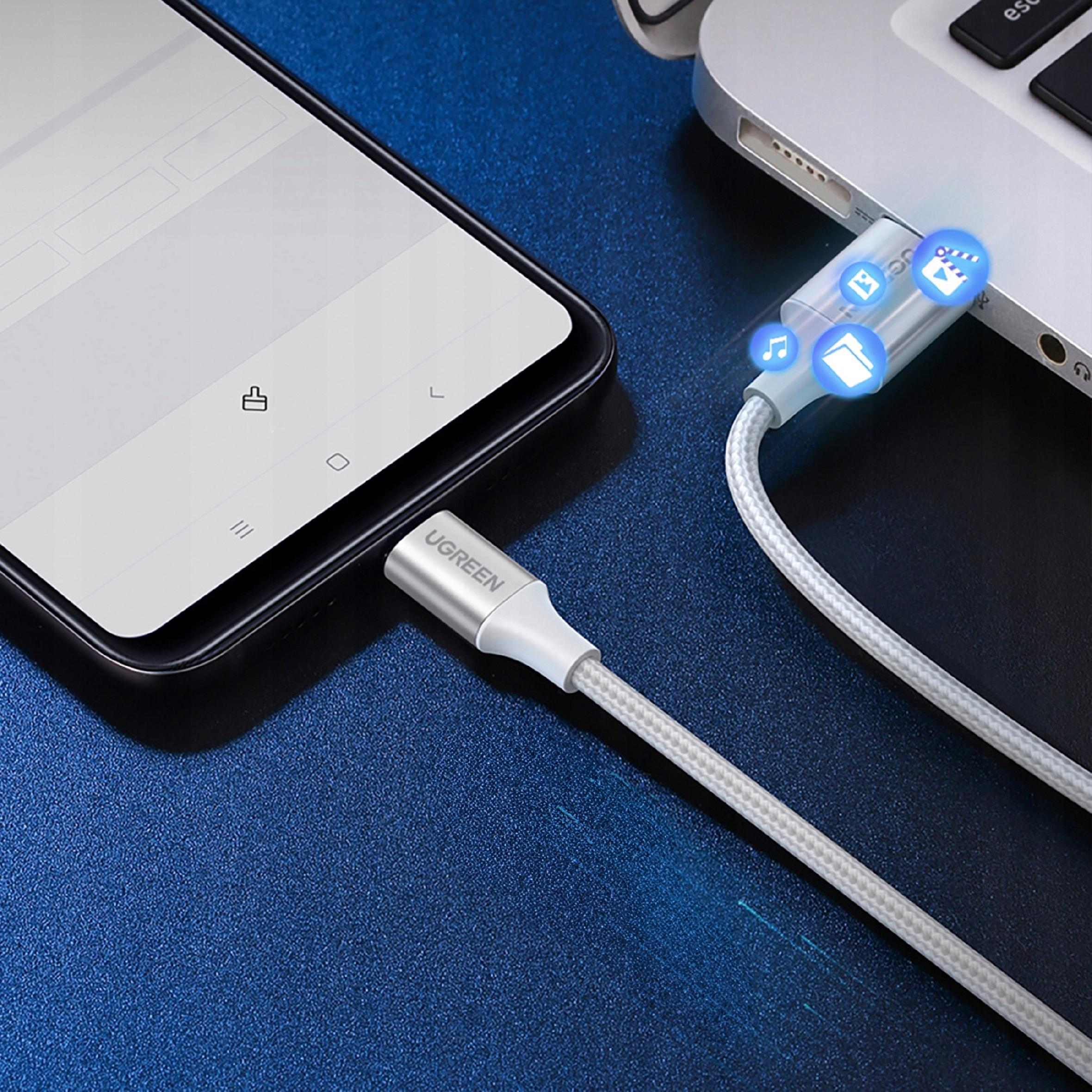 Telefon podłączony do laptopa za pomocą białego kabla UGREEN, z ikonami na ekranie telefonu wskazującymi transfer plików.