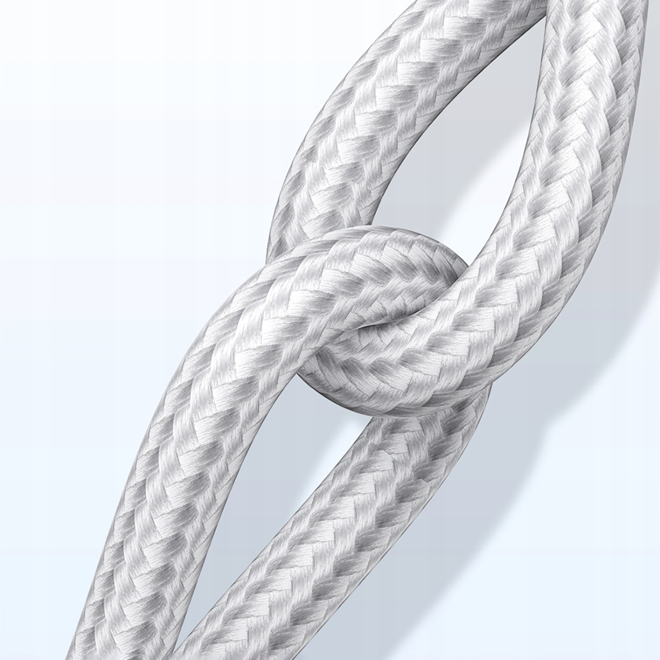 Biały pleciony kabel zawiązany w węzeł. Kabel jest gruby, o szczegółowej fakturze.