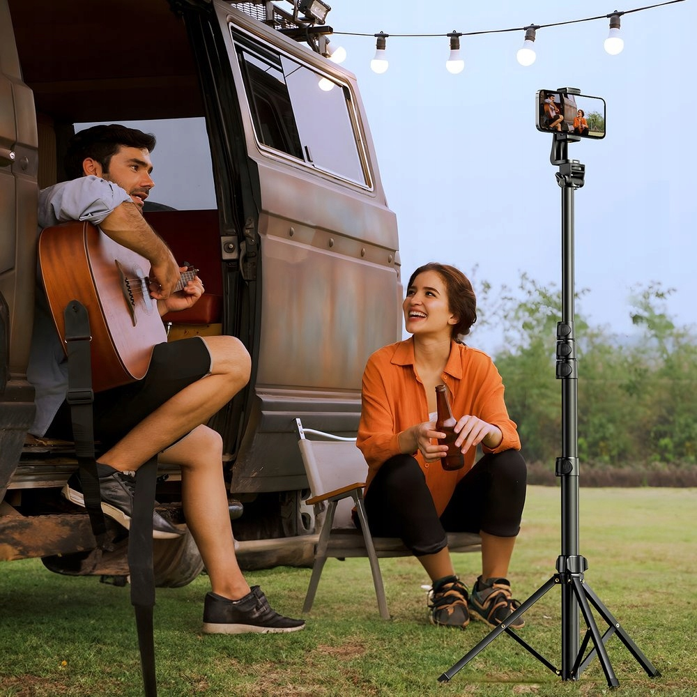 Para z gitarą i piwem, używająca statywu ze smartfonem do nagrywania.