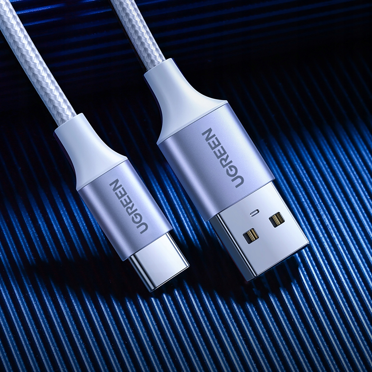 Dwa kable UGREEN obok siebie, jeden USB-C i drugi USB, na niebieskim tle.