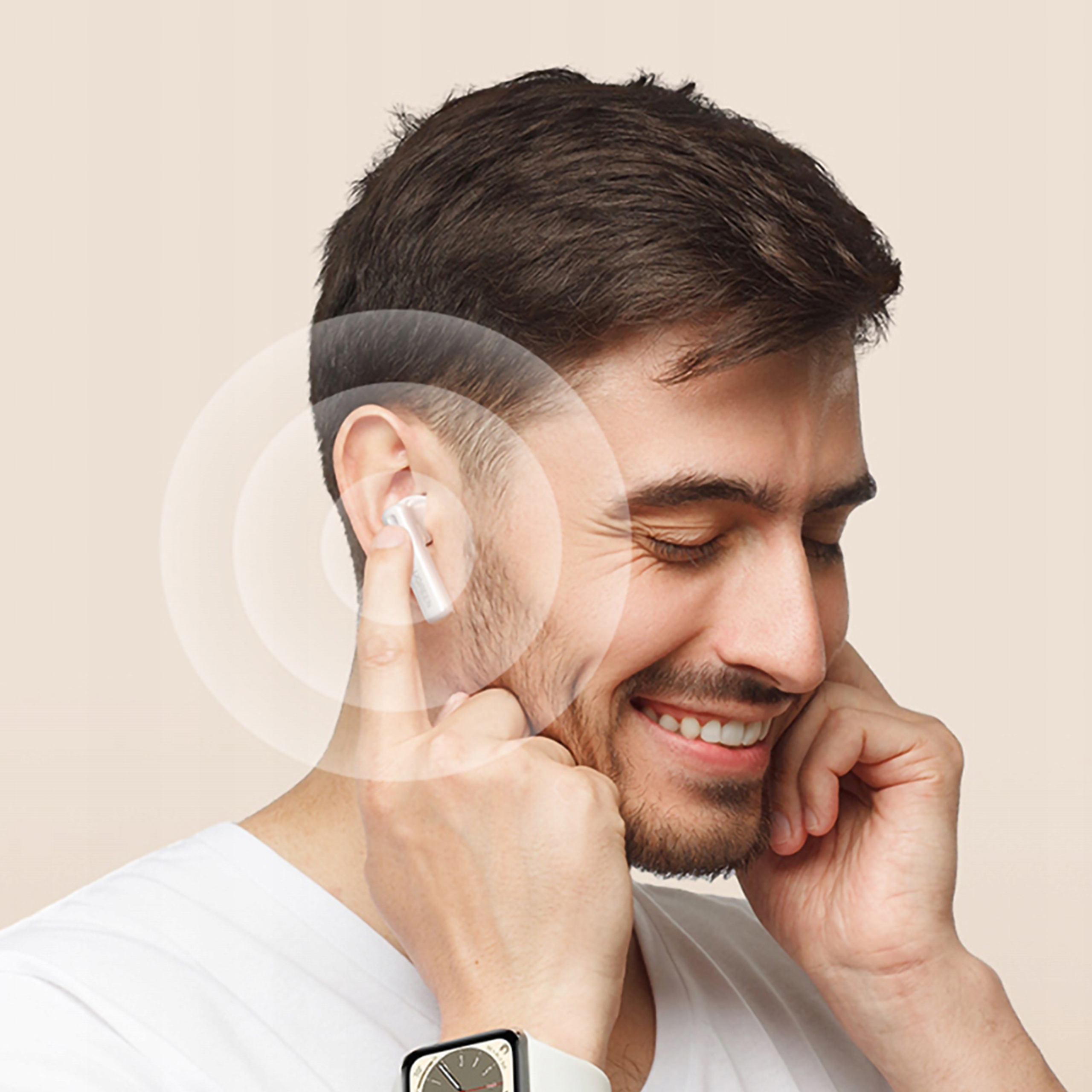 Mężczyzna w białej koszuli uśmiecha się, z bezprzewodowymi słuchawkami w uchu.