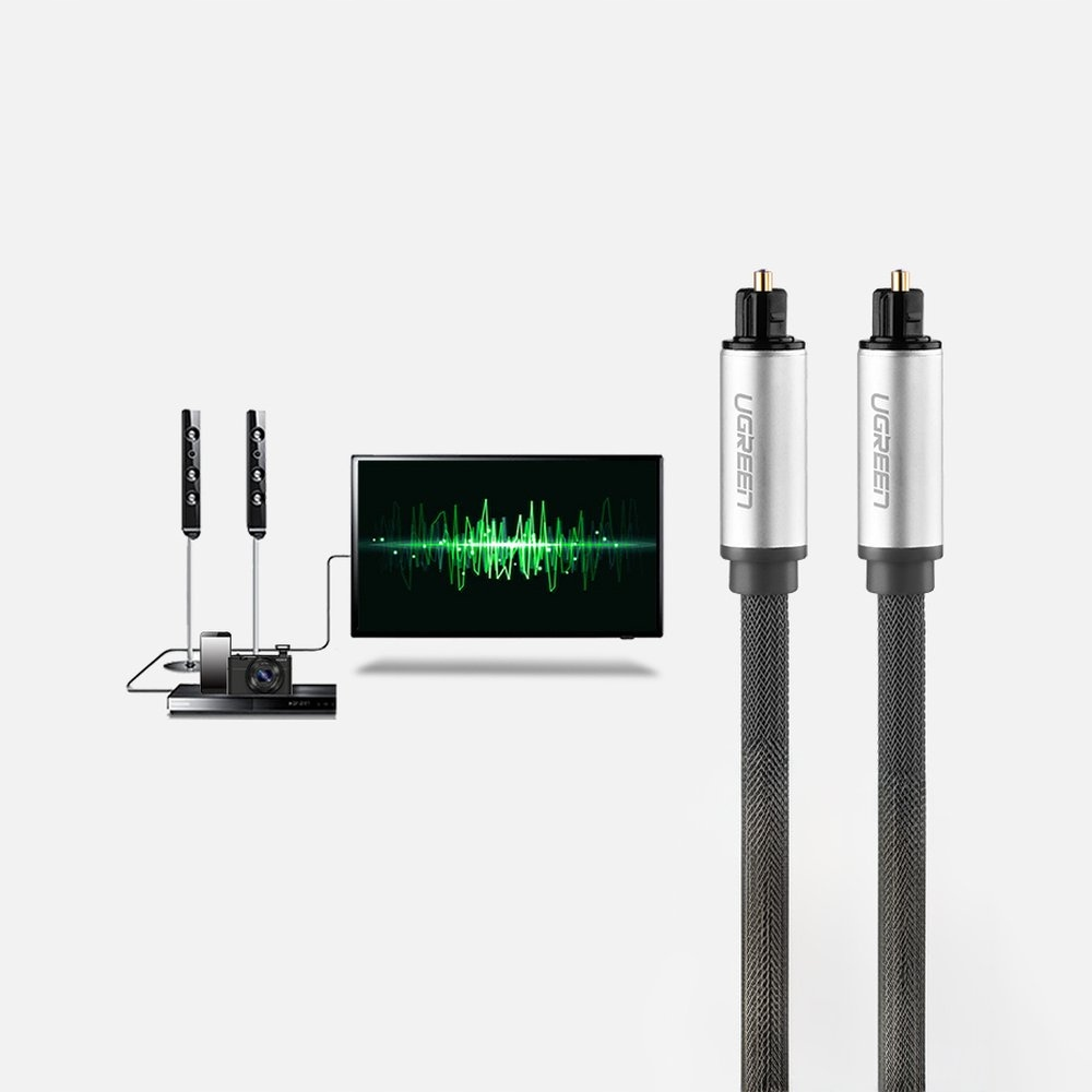 Dwa srebrne i czarne kable audio. Ekran telewizora pośrodku pokazujący falę dźwiękową. Głośniki i urządzenie po lewej stronie.