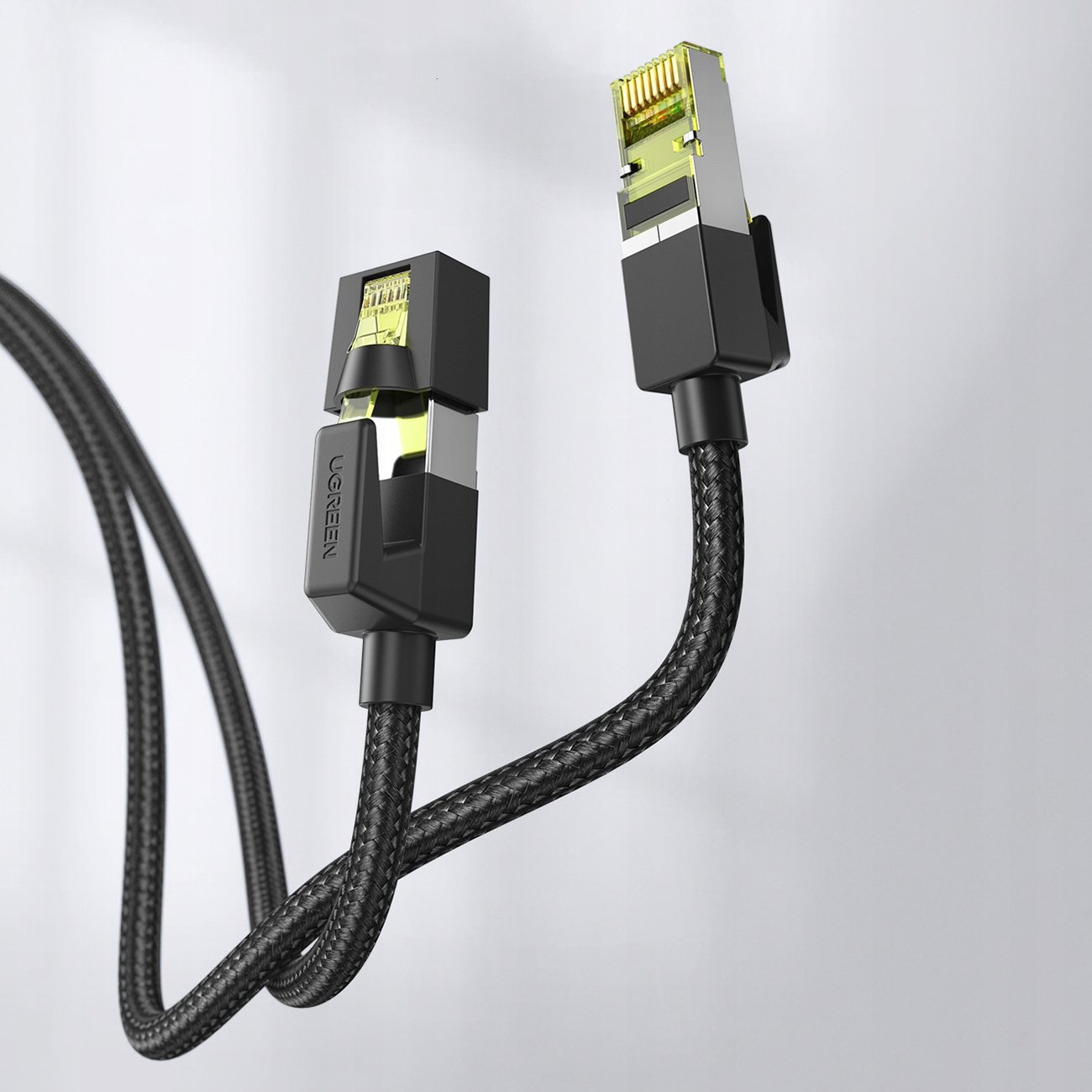 Dwa czarne kable Ethernet z marką UGREEN podłączone do ściany. Złącza są widoczne.