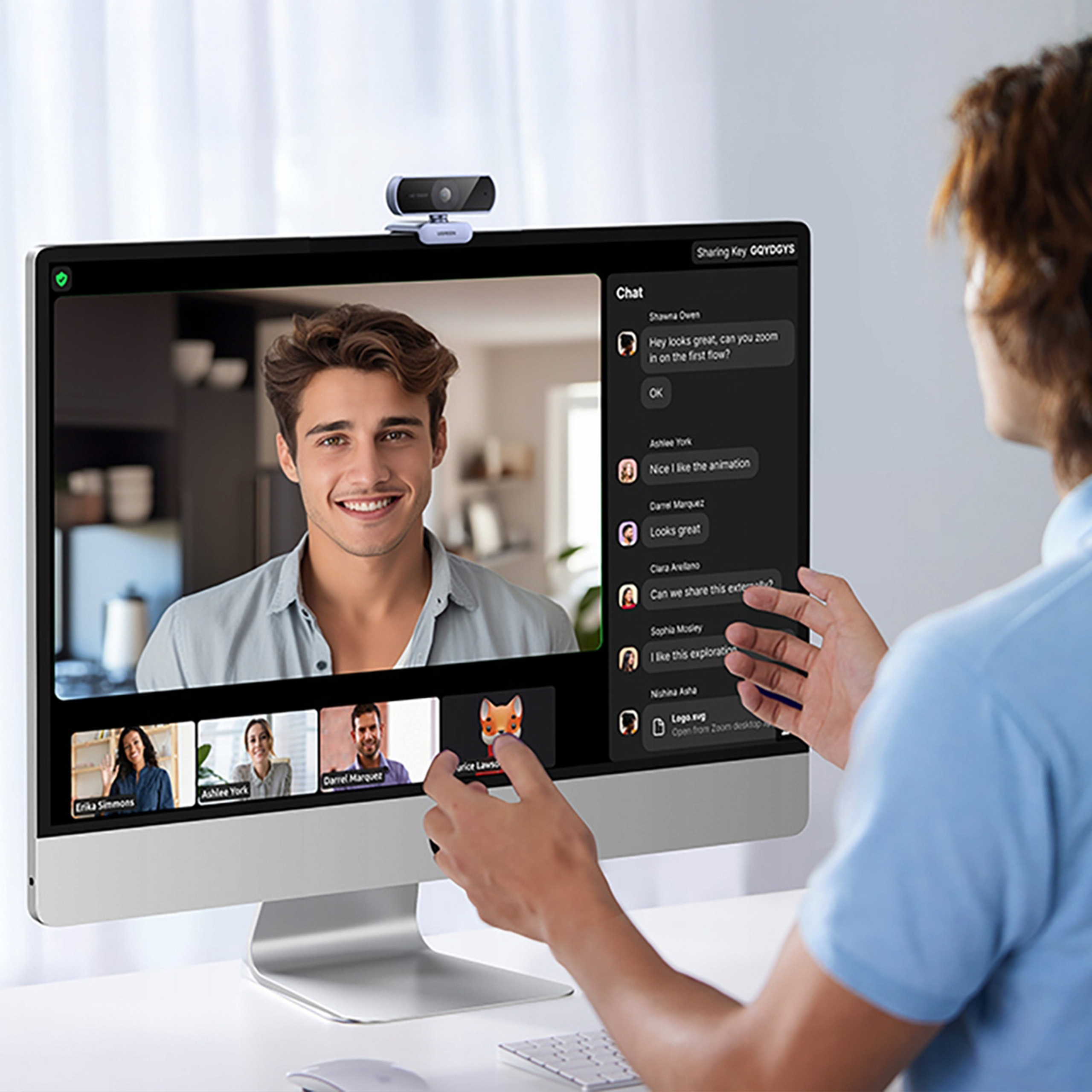 Mężczyzna prowadzi rozmowę wideo. Kamera internetowa jest na górze monitora. Okno czatu pokazuje uczestników.