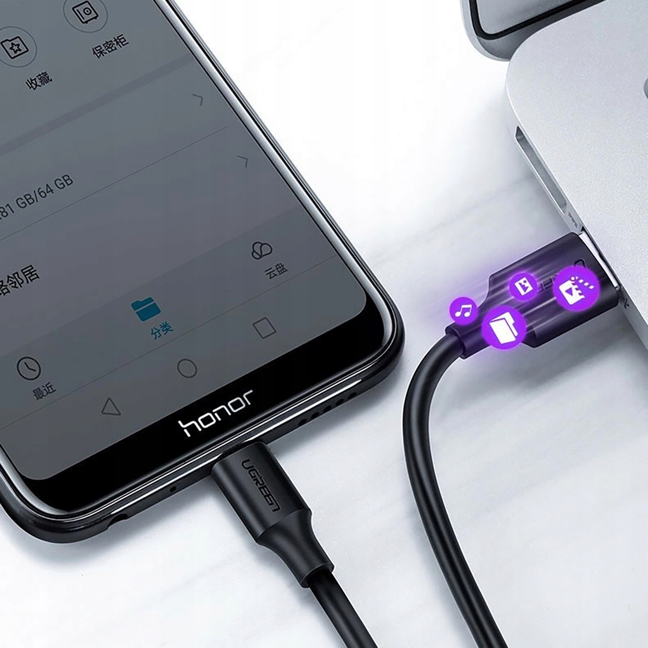 Telefon ładuje się za pomocą czarnego kabla podłączonego do laptopa. Pokazuje ikony muzyki, plików i powiadomień.