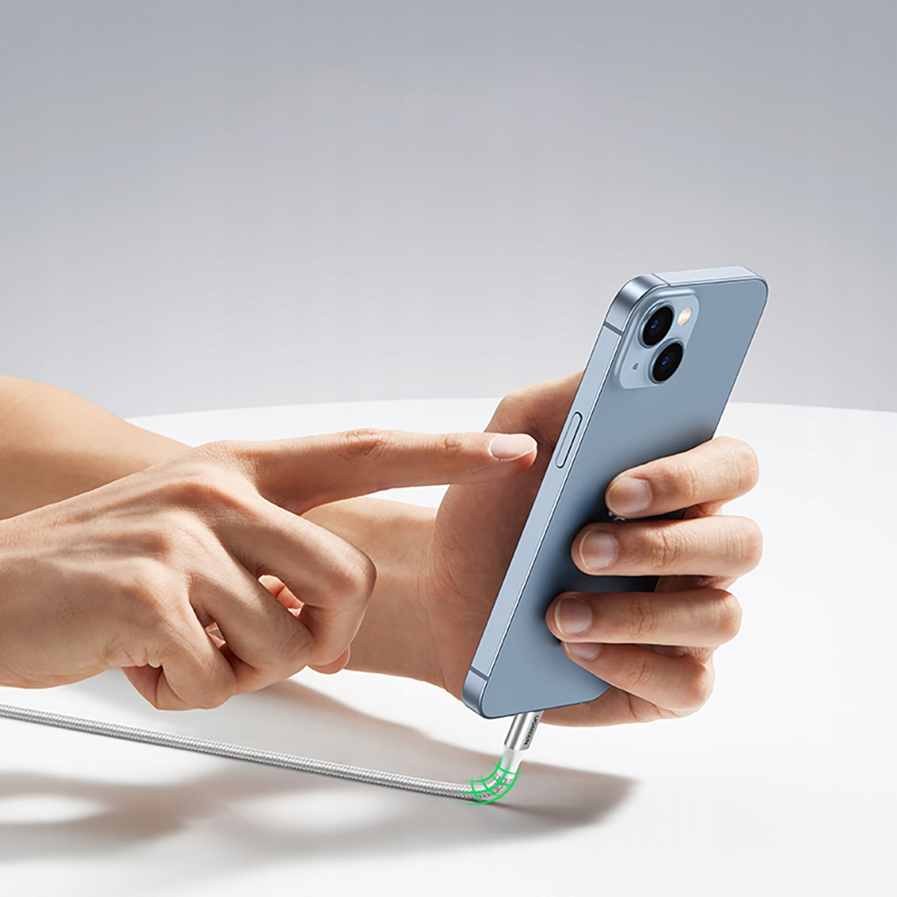 Handen van een persoon die een blauwe telefoon vasthouden. De telefoon is aangesloten op een zilveren USB-C-kabel.