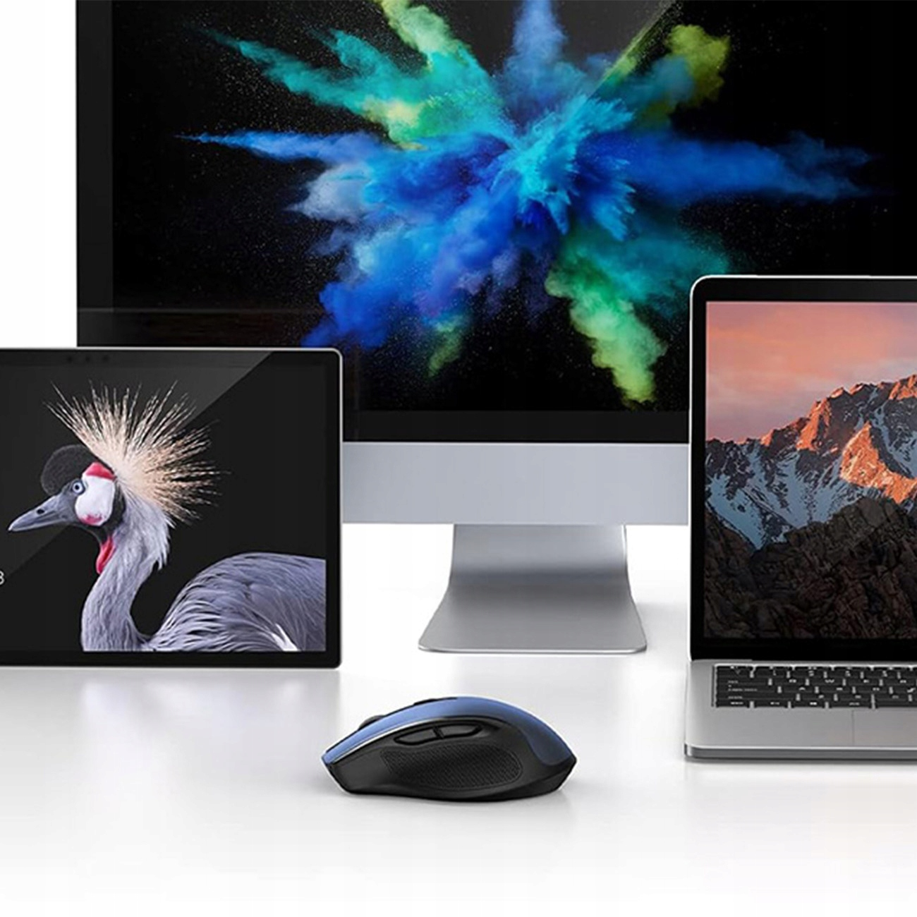 Niebieska mysz znajduje się przed laptopem, tabletem i monitorem. Wyświetlające różne obrazy.