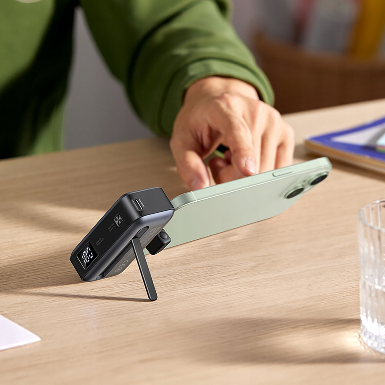 Power bank ładuje telefon. Power bank ma wyświetlacz pokazujący 100% naładowania.