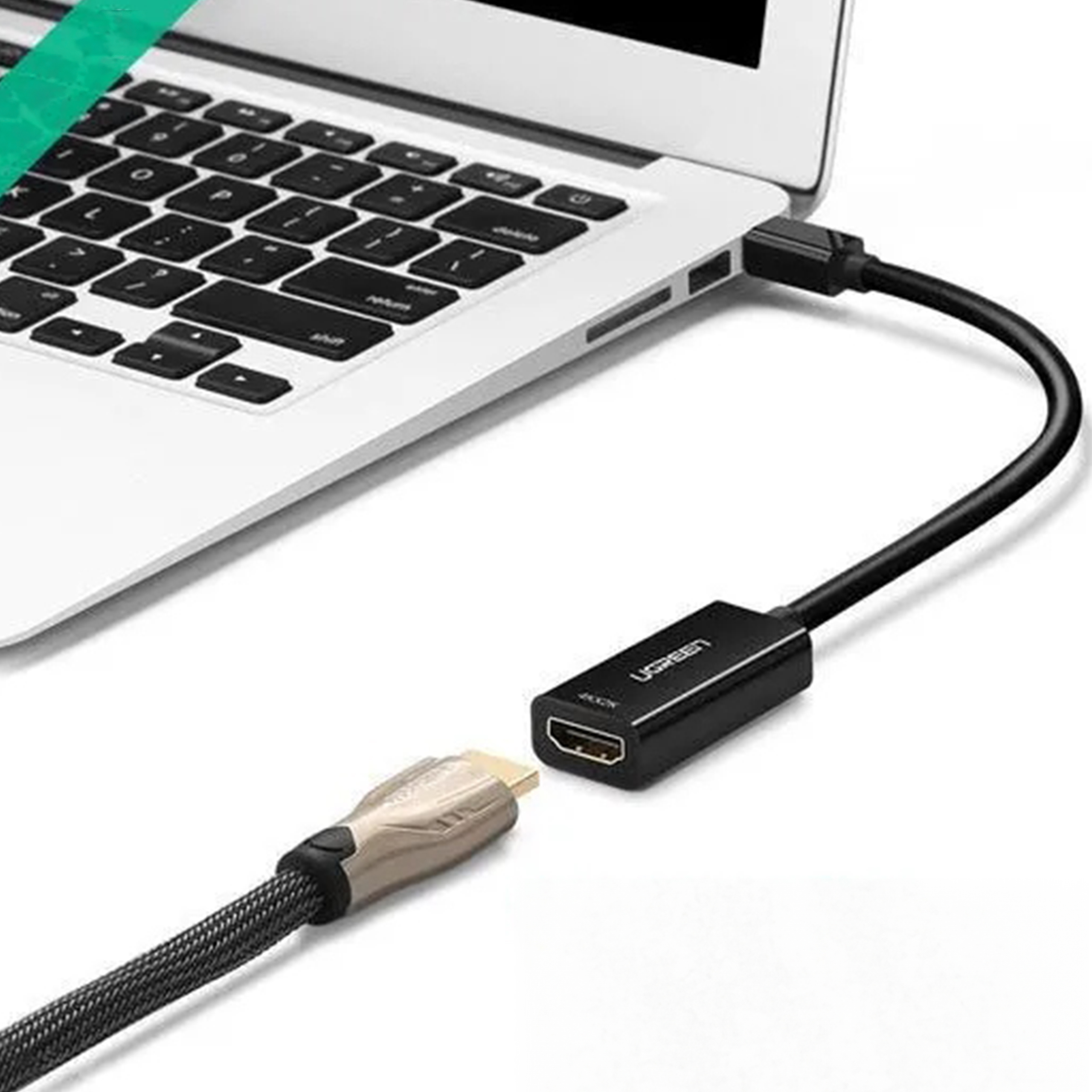 Laptop podłączony do czarnego adaptera UGREEN. Adapter łączy się ze złotym kablem HDMI.