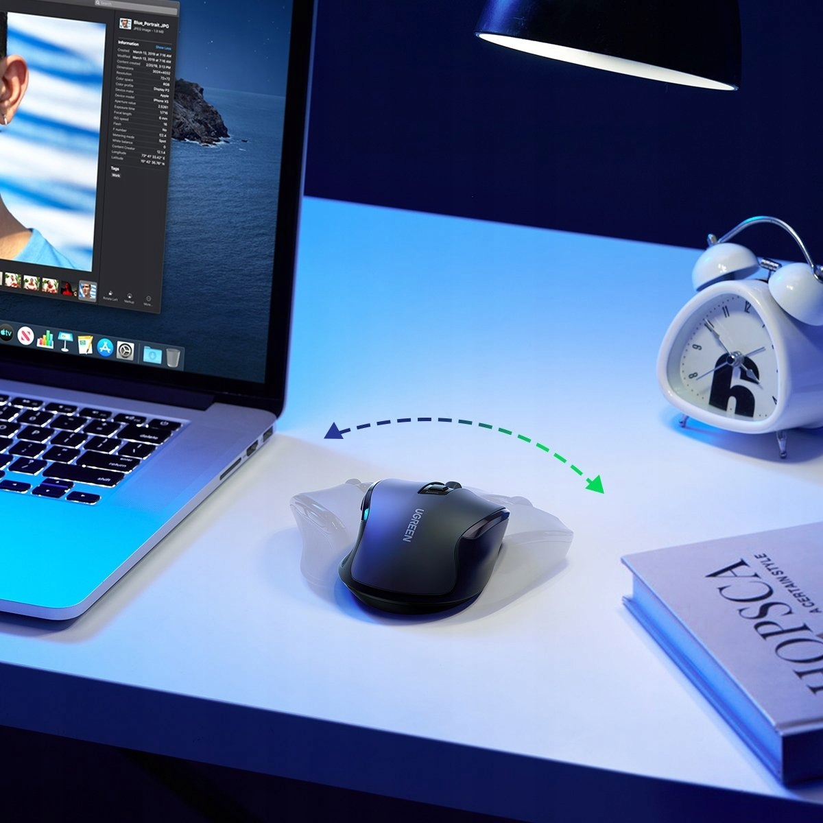 Czarna mysz bezprzewodowa UGREEN na białym biurku. Na biurku znajduje się również laptop i budzik.