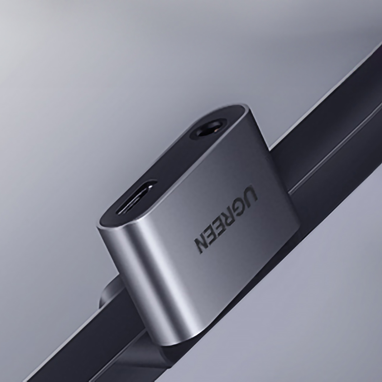Srebrny adapter UGREEN z gniazdem słuchawkowym i portem USB-C na odblaskowej powierzchni.