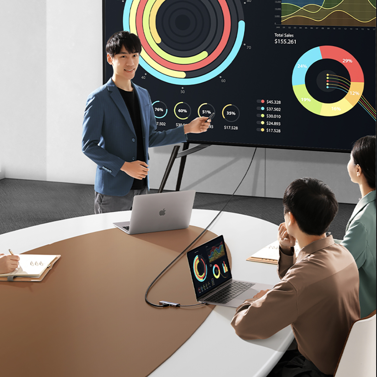 Prezentacja w toku, mężczyzna prezentuje dane dwóm kolegom. Laptop jest podłączony do dużego ekranu.