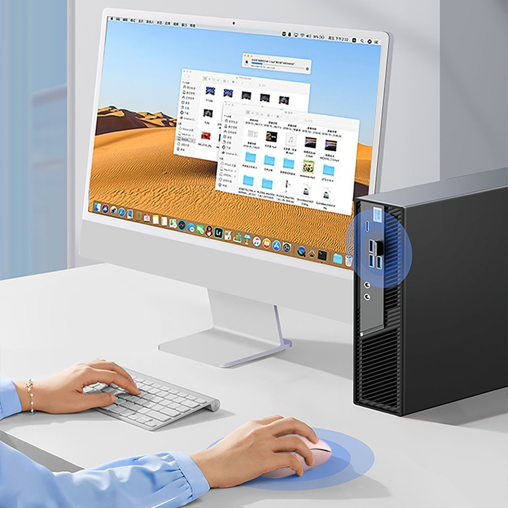 Le mani usano un mouse e una tastiera rosa accanto a un computer desktop e un monitor con finestre aperte.