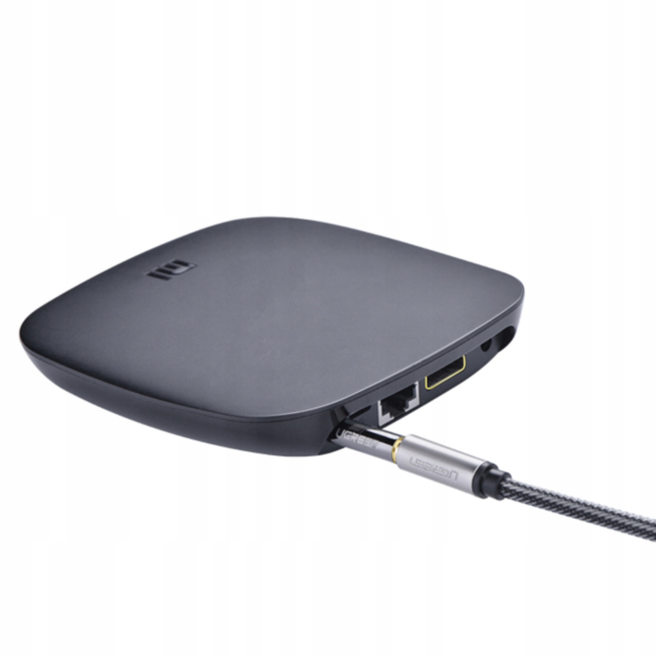 Czarne kwadratowe urządzenie z wpiętym srebrnym kablem, białe tło.